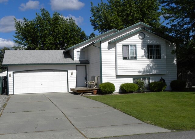  Front of a well-maintained, white bi-level home with healthy grass. 