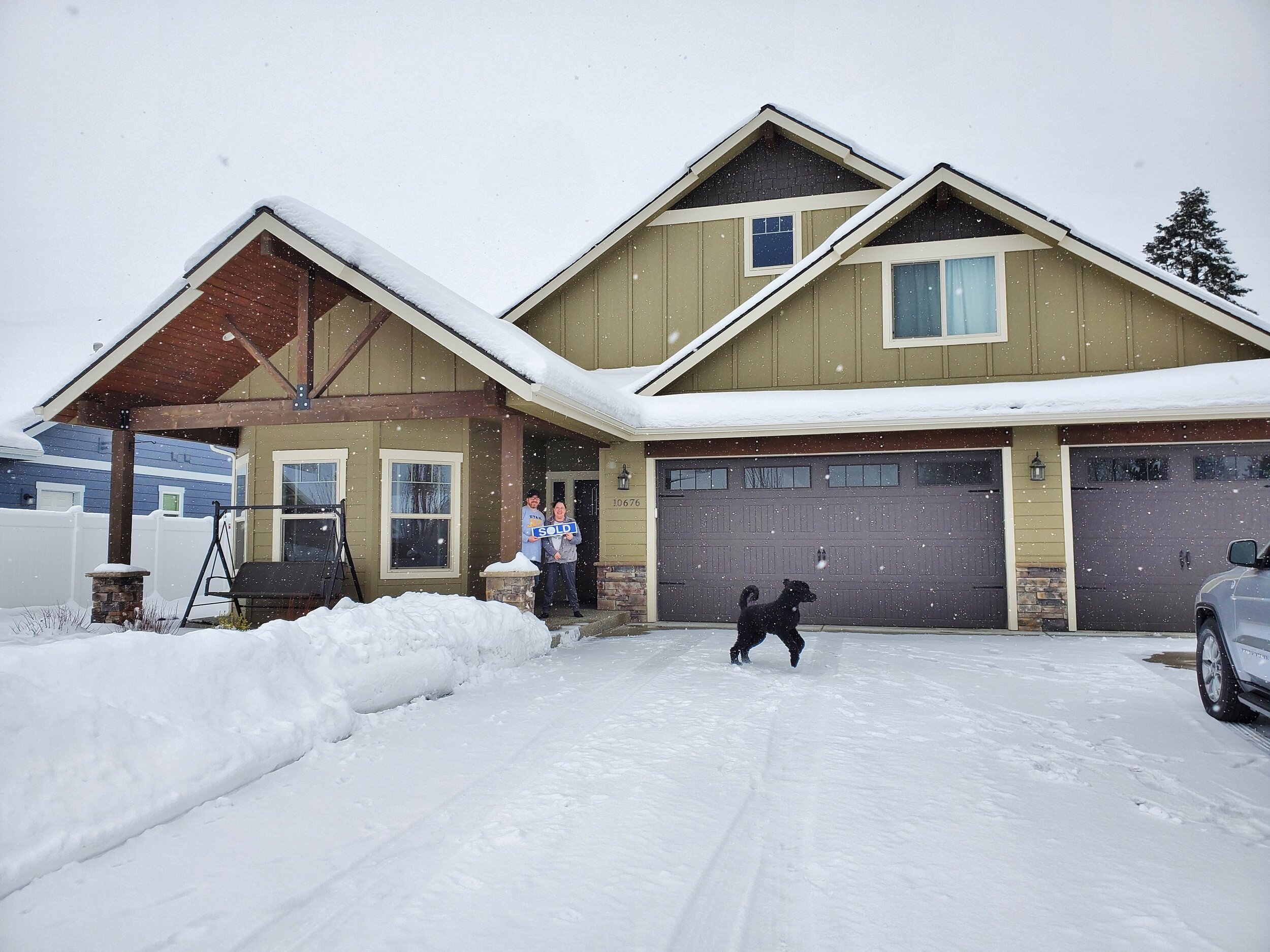  Craftsman style home with dog and couple out front in the snow. 