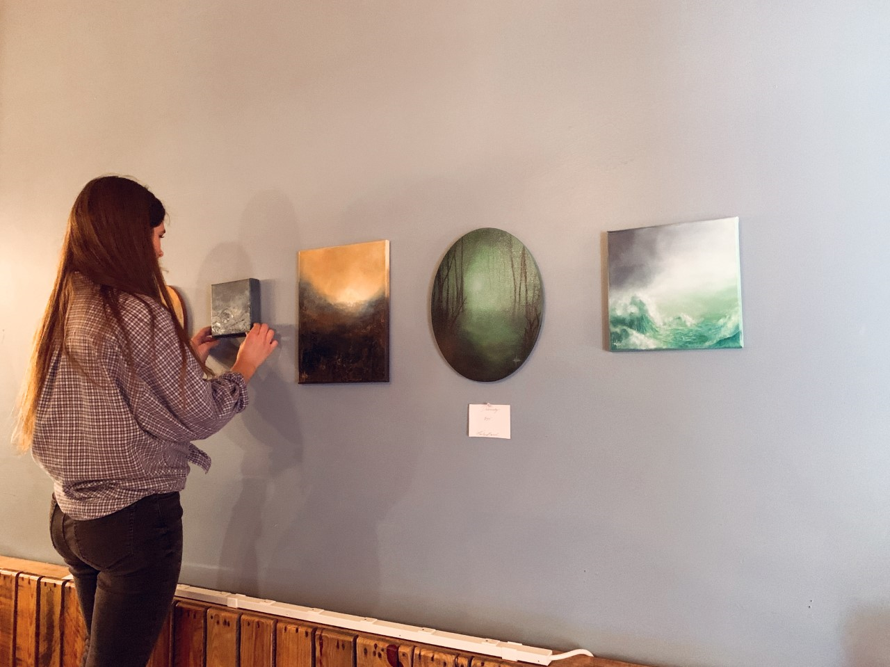 Kailyn Burch hangs her artwork at The Mill Coffee. Photo by Sydney Pressley.