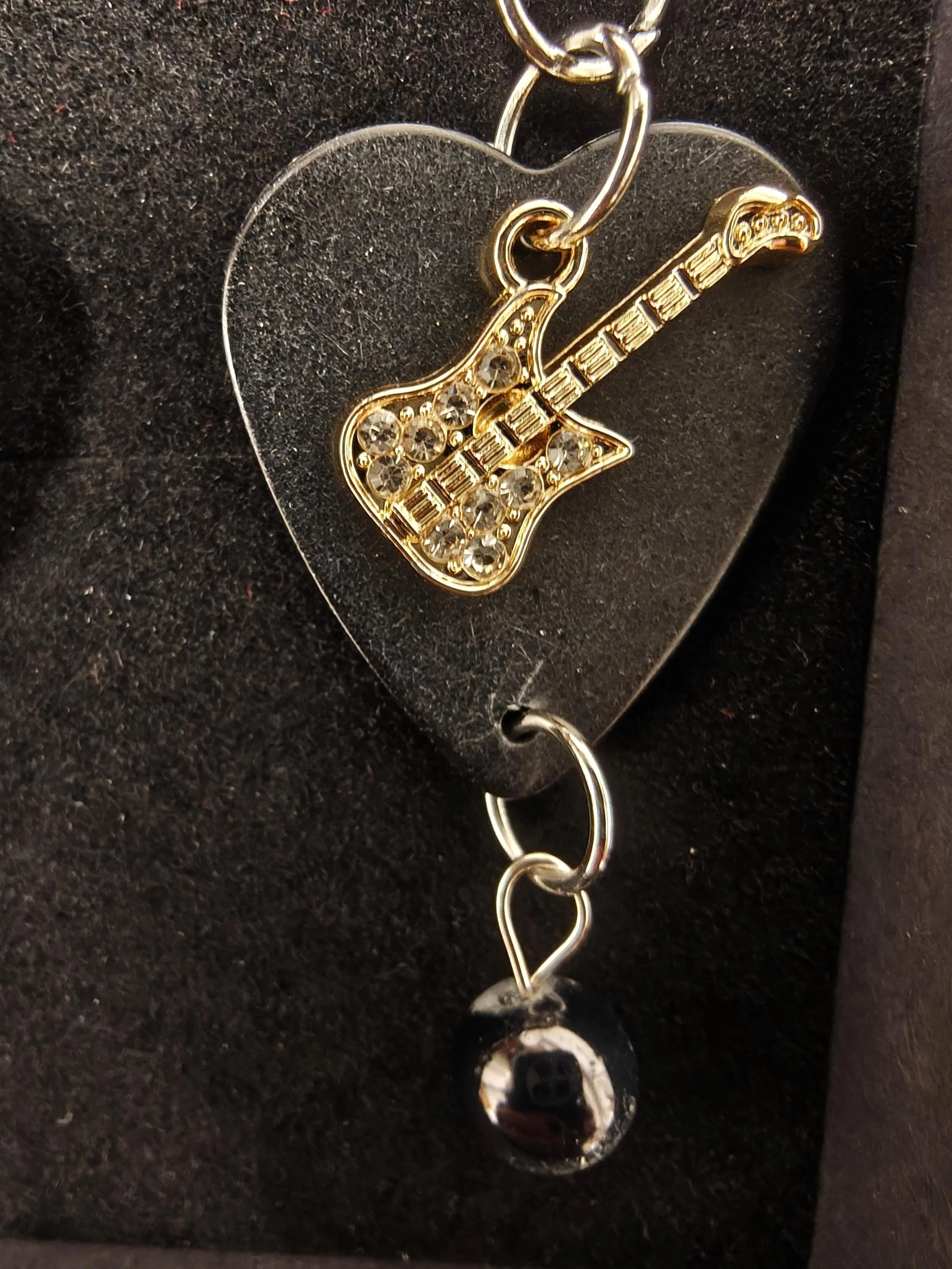 Gold colored metal guitar pick earrings with a pearl