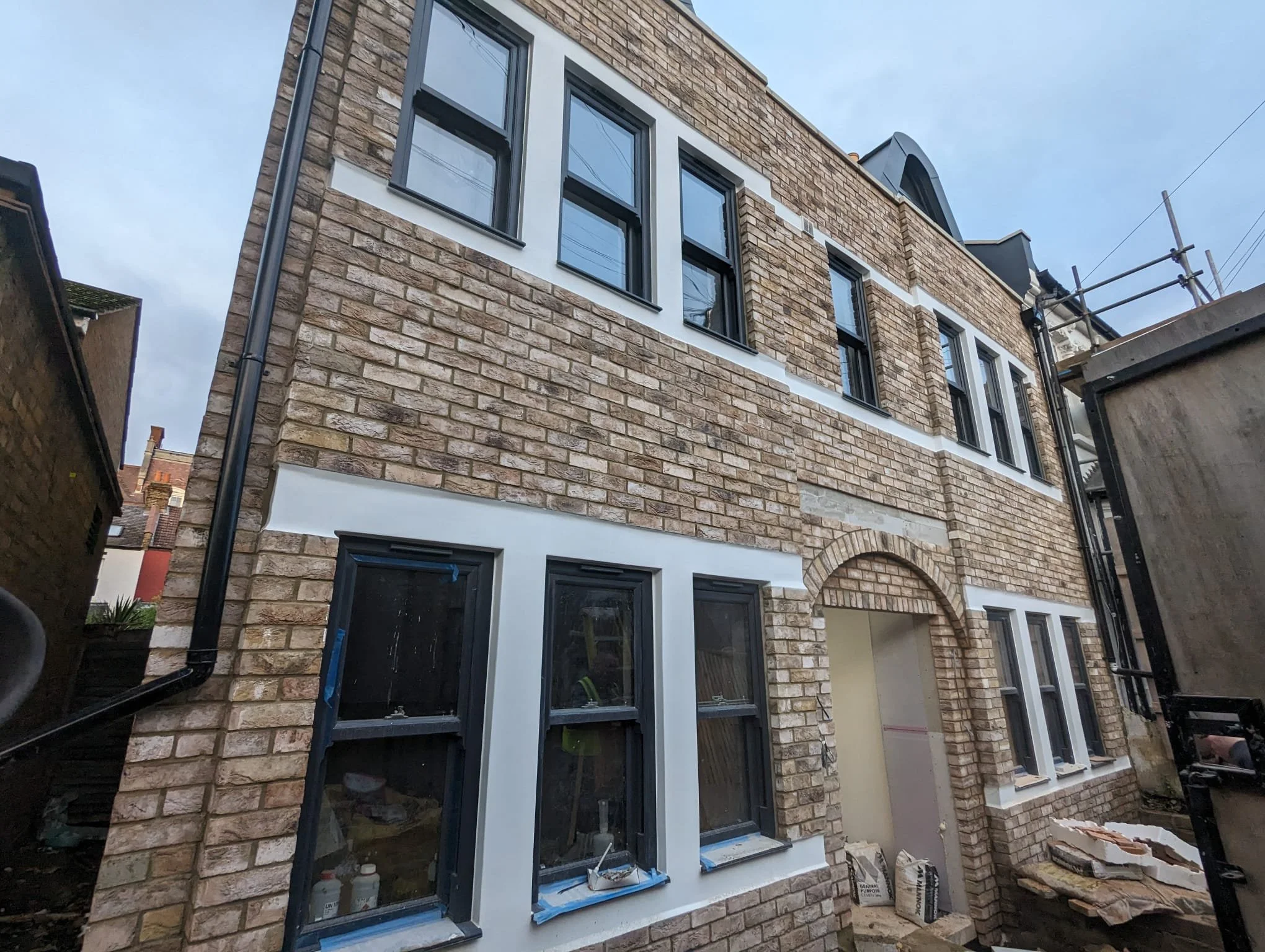 Completed exterior brick slip installation on a two-storey building facade with dark window frames