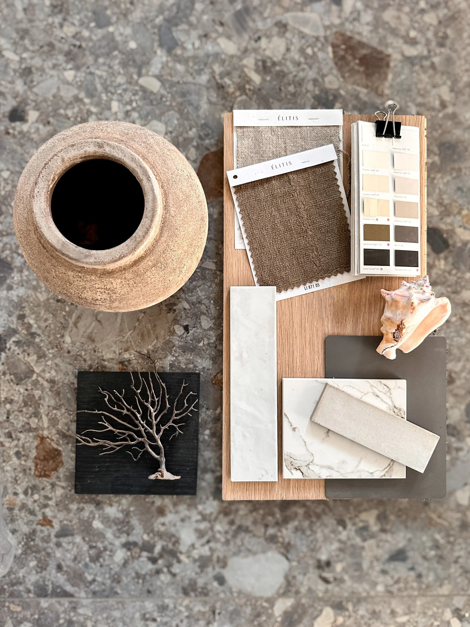 Farb- und Materialmuster, Textilproben, Fliesen und Dekorationselemente für Innendesign auf Holztisch, mit Kaffetopf im Hintergrund auf Steinterrasse