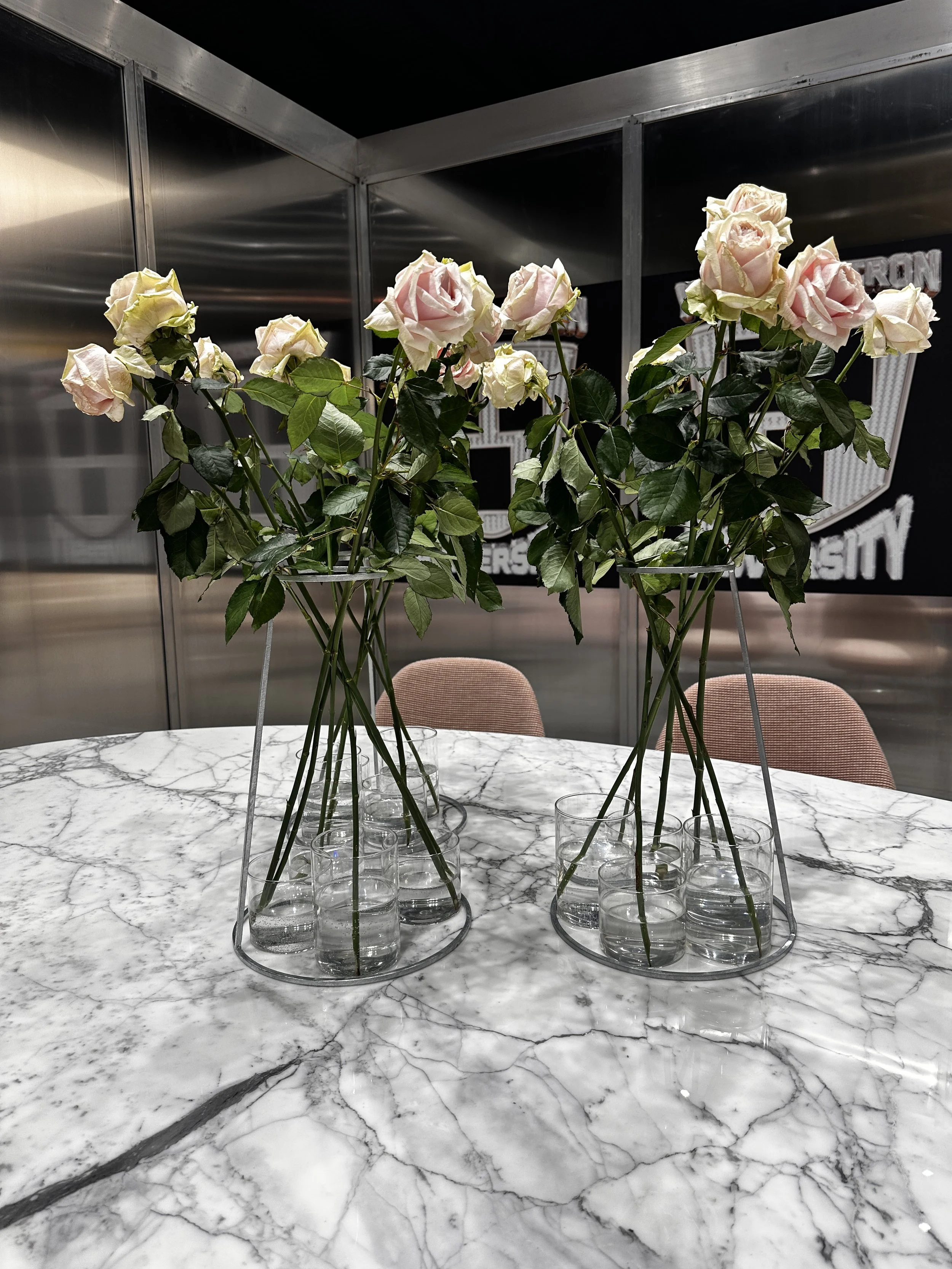 Weiße Rosen in Glasvasen auf einem Marmortisch im modernen Raum.