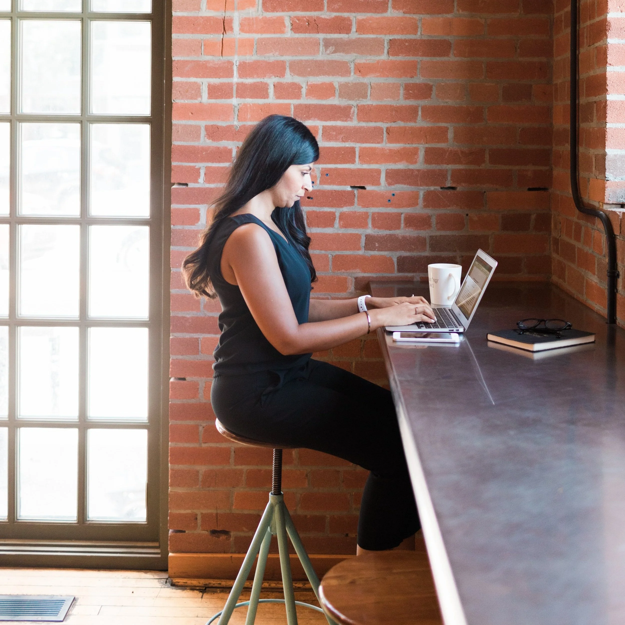 Saira of Hrology sitting at a laptop looking at The Workplace Investigation Bootcamp