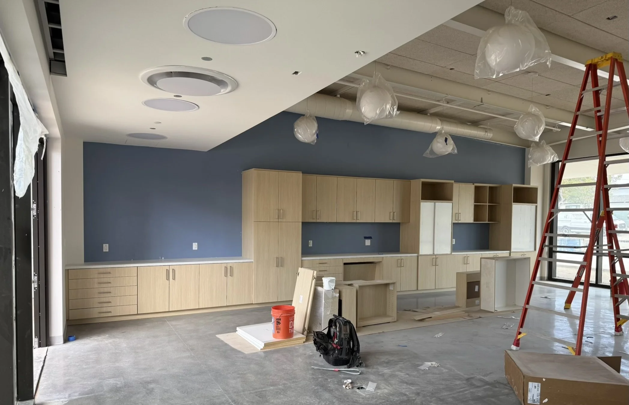 Custom classroom cabinetry and millwork mid-installation at a Redondo Beach private school, with wall cabinets and base units set against a blue accent wall