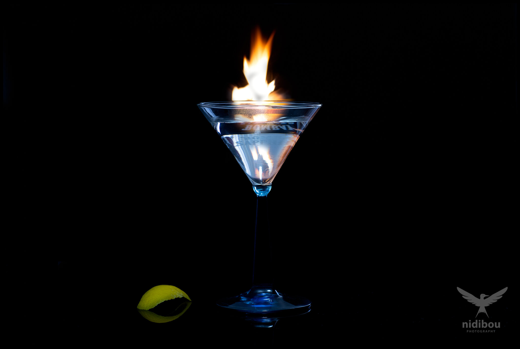 Martini cocktails glass with a twist and a flame