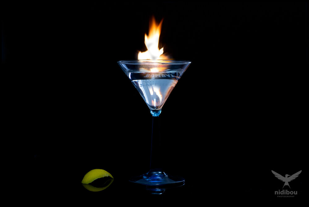Martini cocktails glass with a twist and a flame