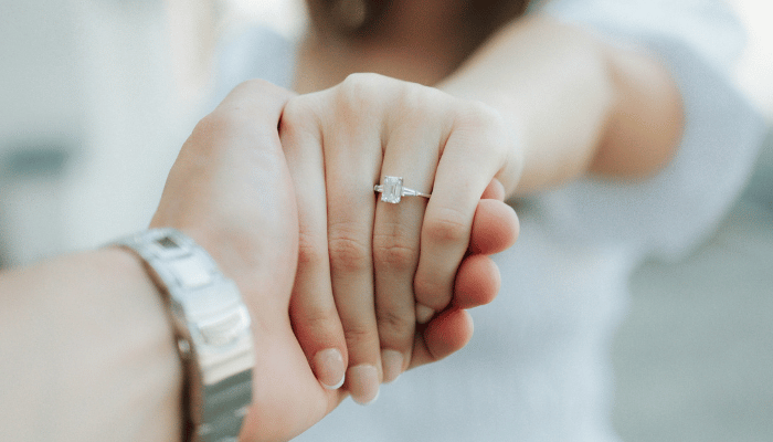 Couple holding hands and showing an engagement ring for engagement announcement ideas