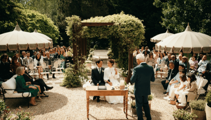 Bride and groom sitting together during an outdoor wedding ceremony with their guests