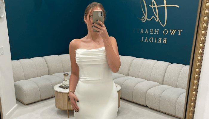 Bride trying on a sleek strapless wedding dress with a draped neckline during a bridal appointment
