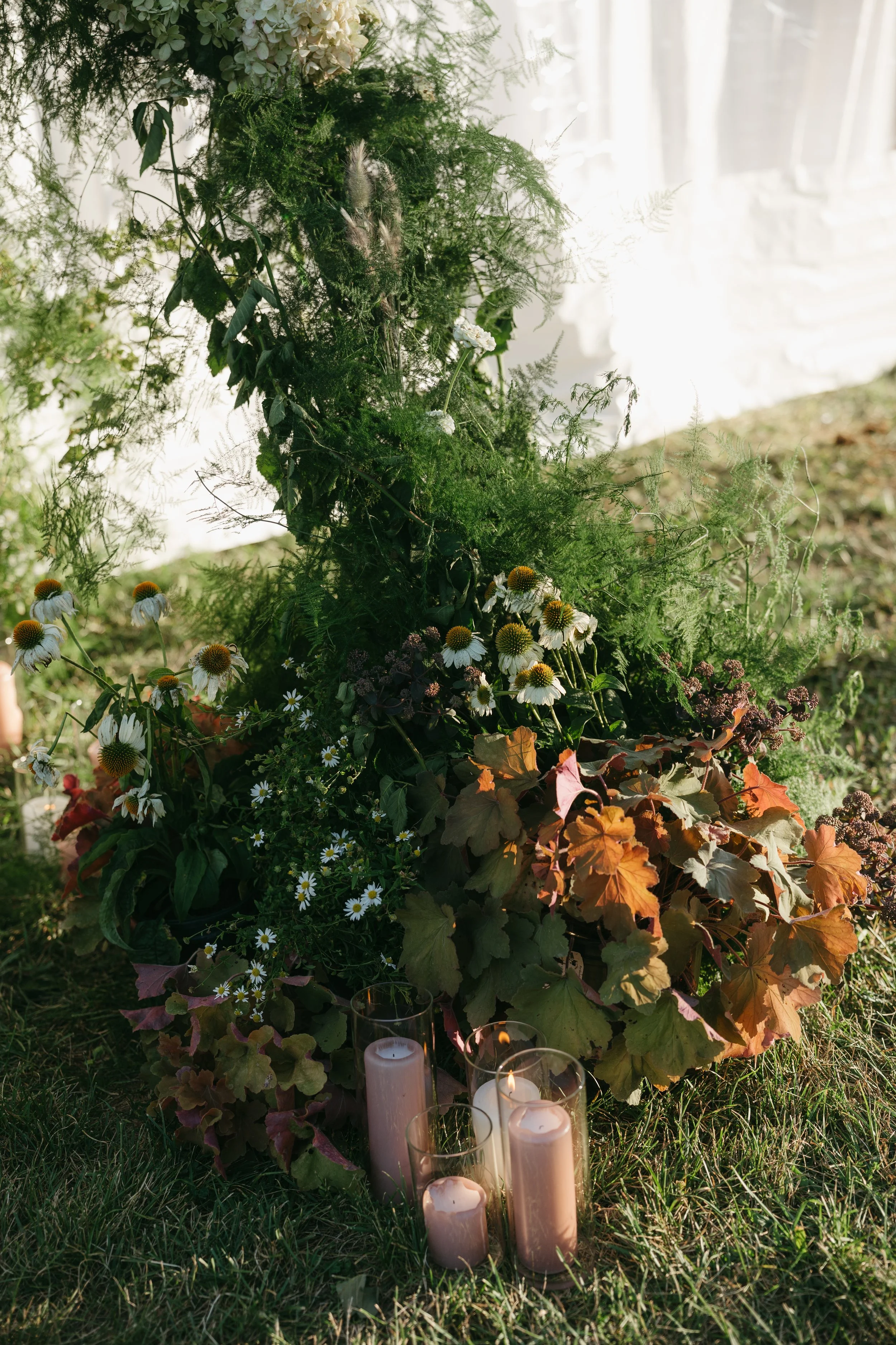 Meadow-style ground floral arrangement with seasonal blooms and pillar candles
