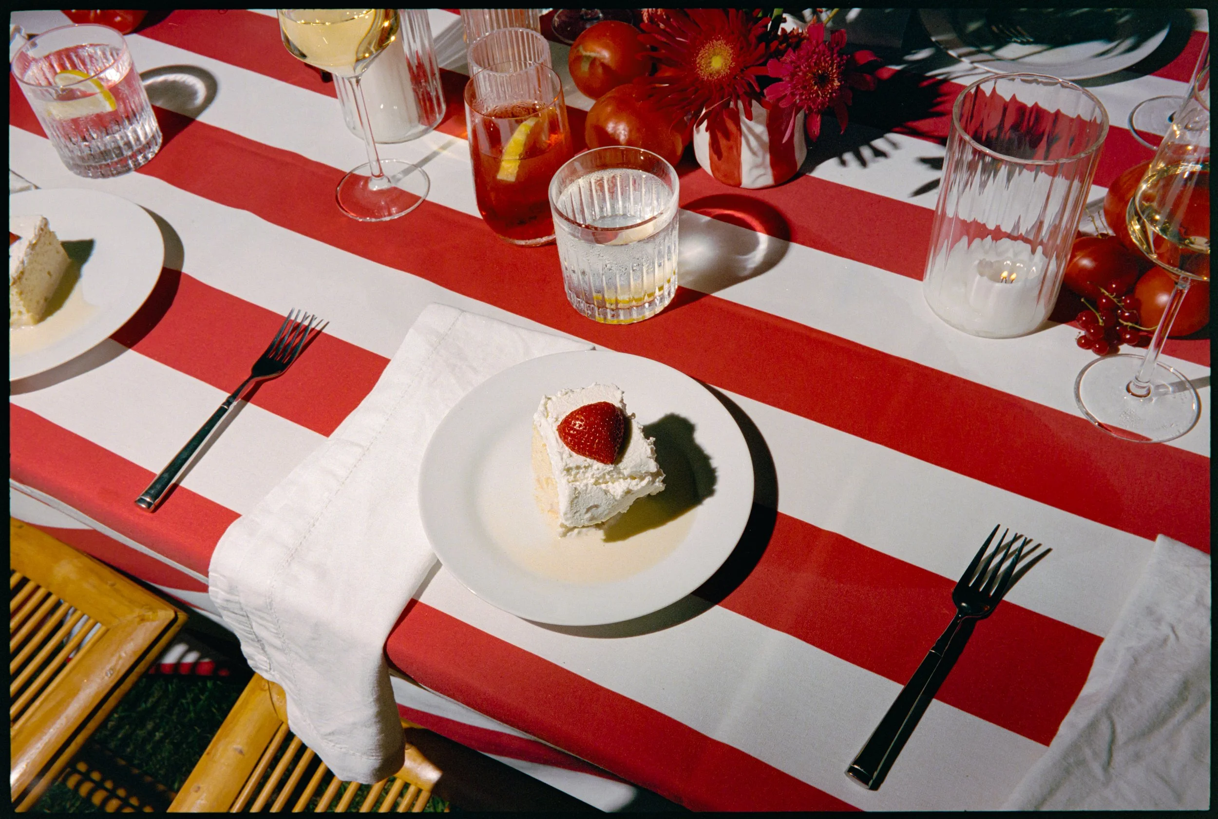 Striped reception table detail with dessert plate, glassware, and red-and-white linens
