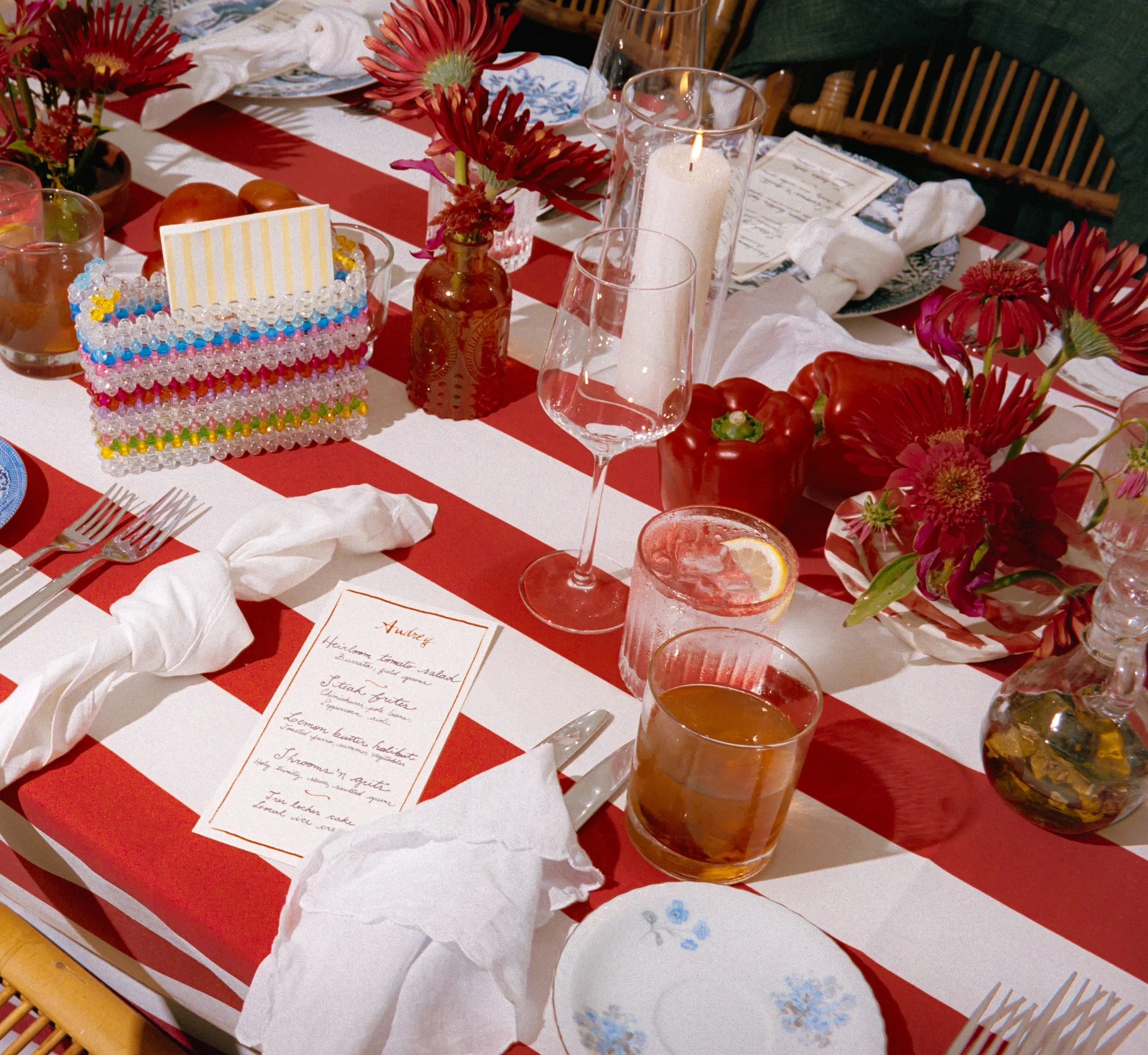 Striped reception table styled with menus, candles, and vibrant floral centerpieces