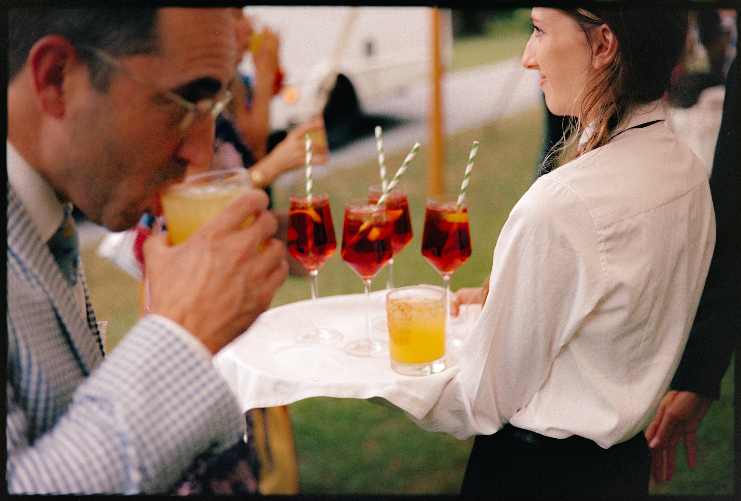 Guests enjoying cocktails served on tray during outdoor estate wedding reception