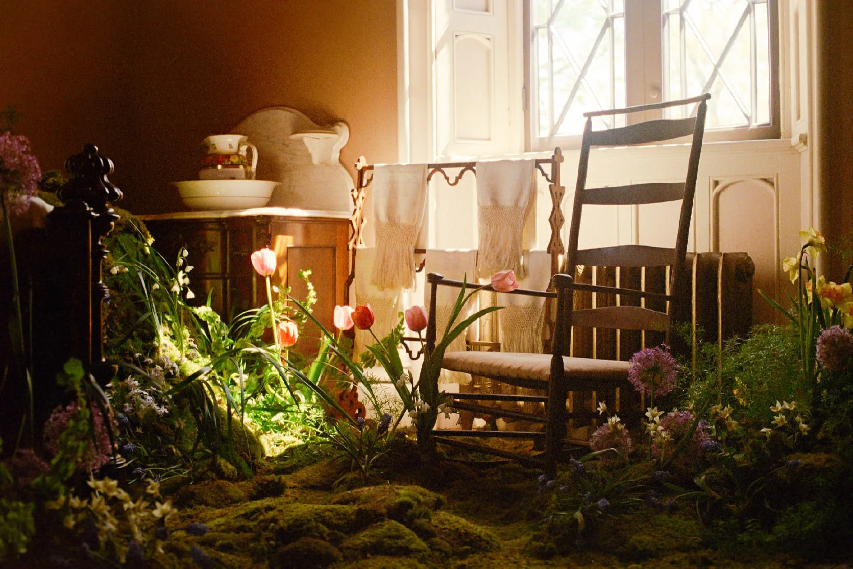 Sunlit corner of dreamy room has tulips, textured allium and greenery, surrounded by moss    