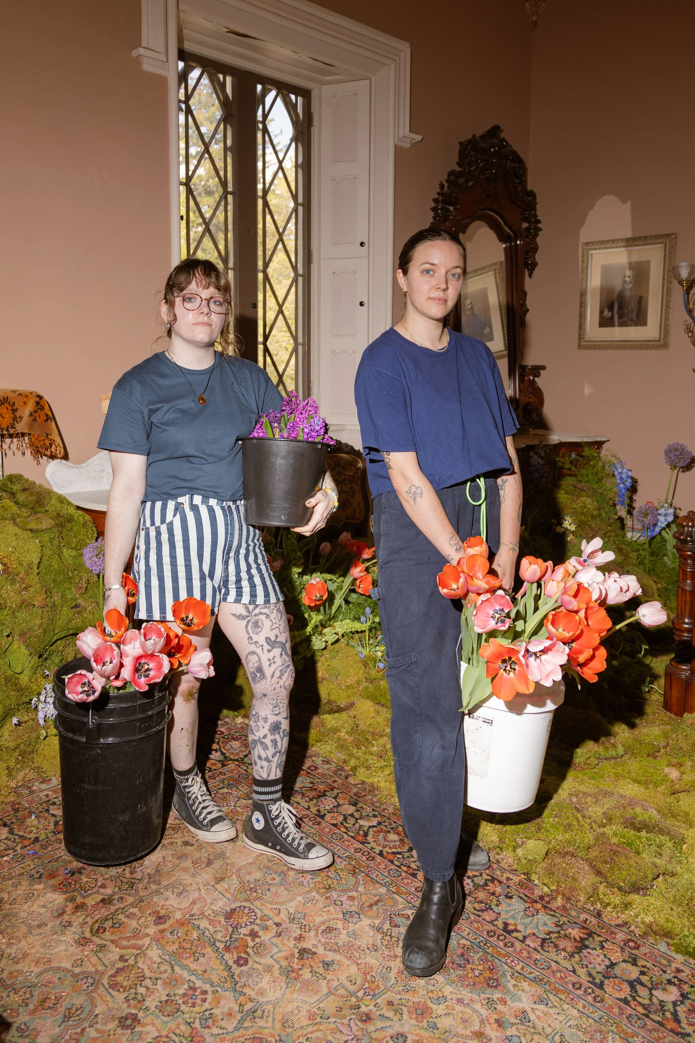  Dramatic photo of two designers holding full buckets of timeless flowers and colorful blooms   