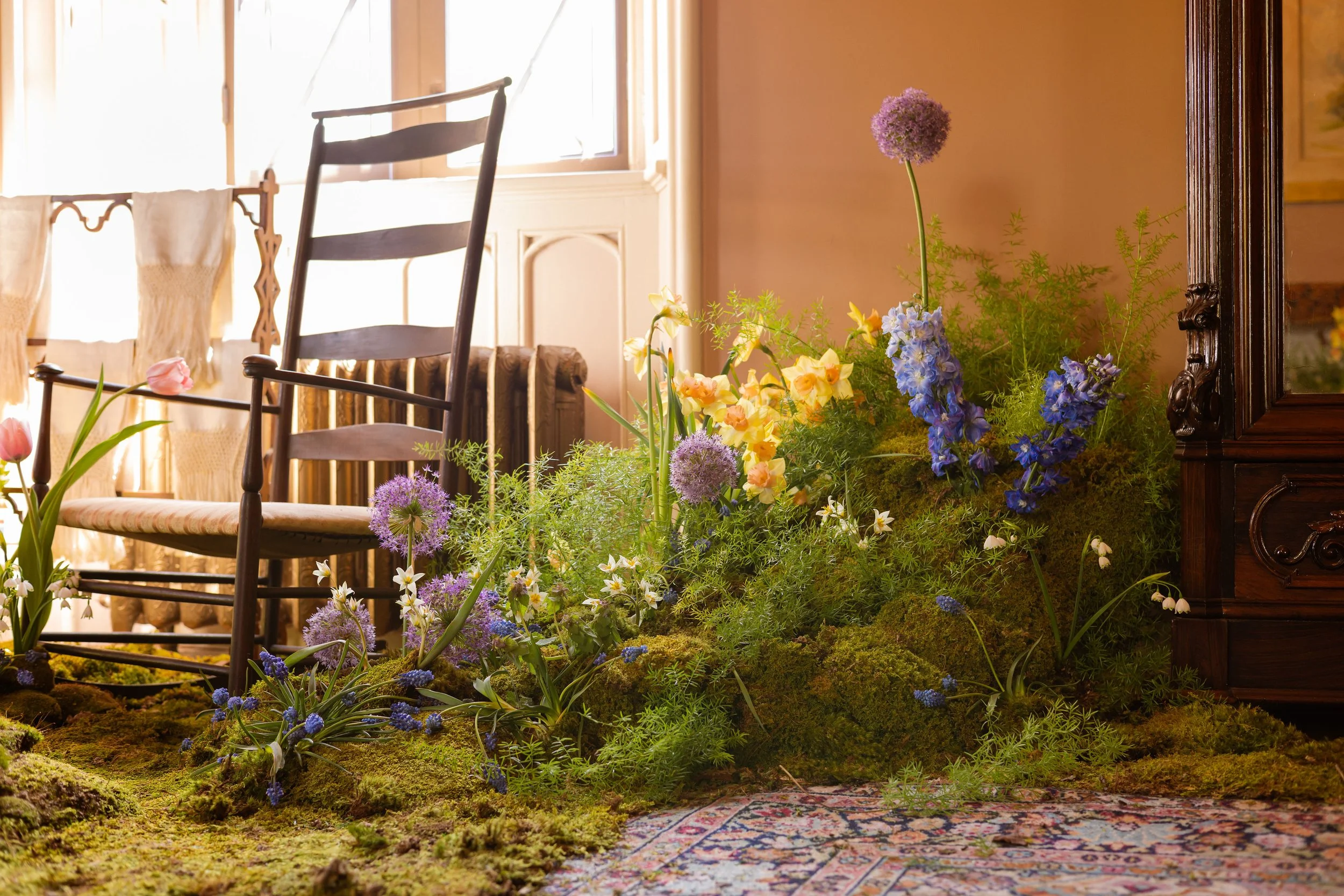  Vintage wooden chair next to whimsical installation with flowing grasses, tulips, alliums and lush wildflowers 