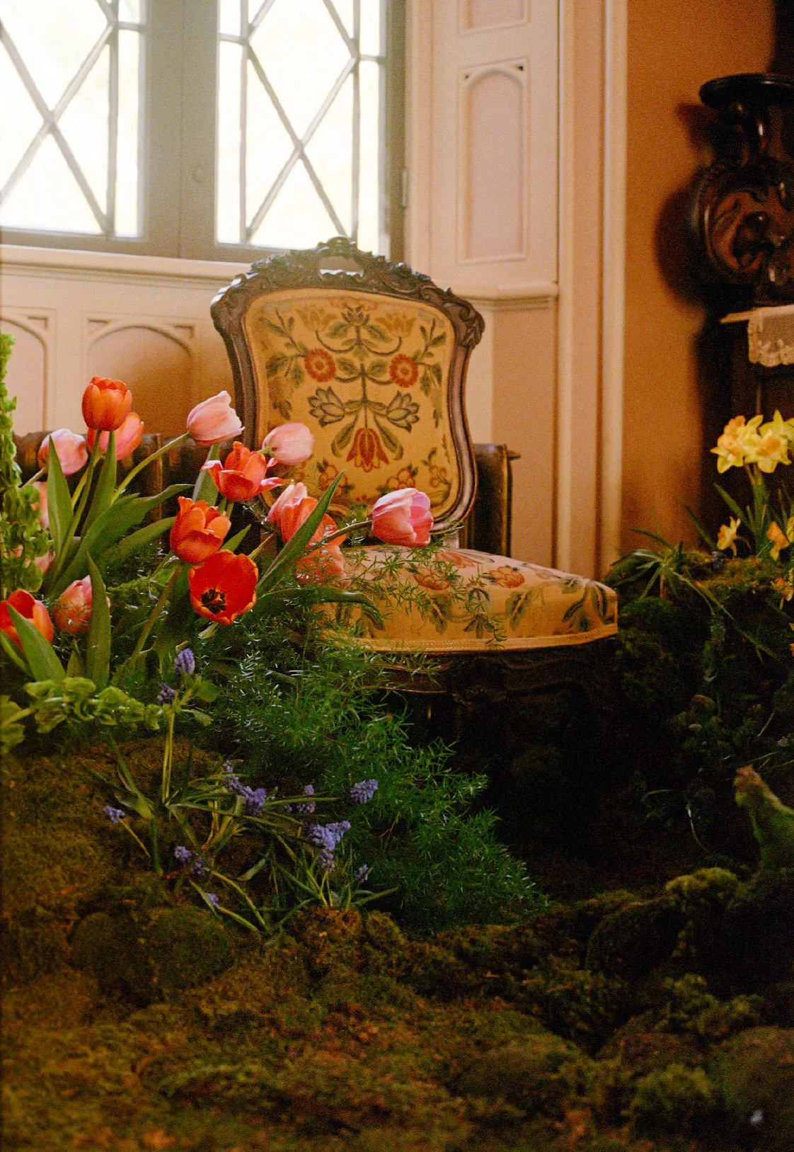  Antique chair next to airy asparagus ferns, and playful pink and red tulips   