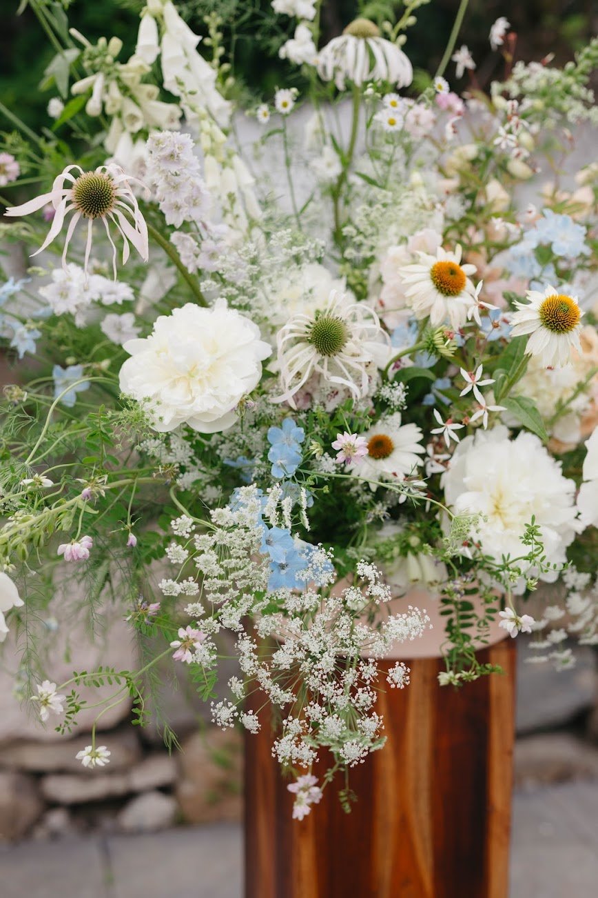  Elegant bouquet on pillar featuring wispy  white blooms and dainty foliage  