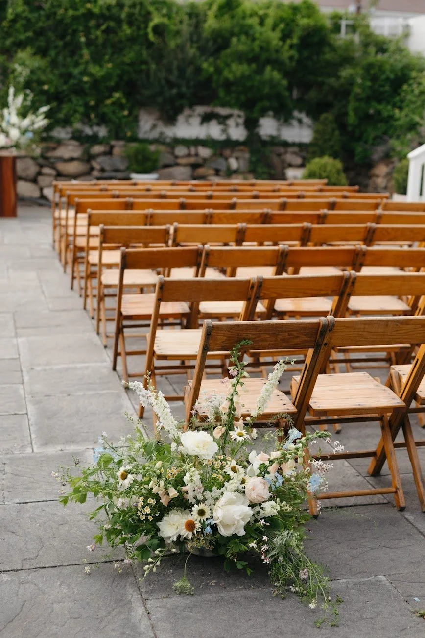  Asymmetrical, whimsical floral arrangement with green leaves crawling out and intimate blossoms in the center on floor of aisle    