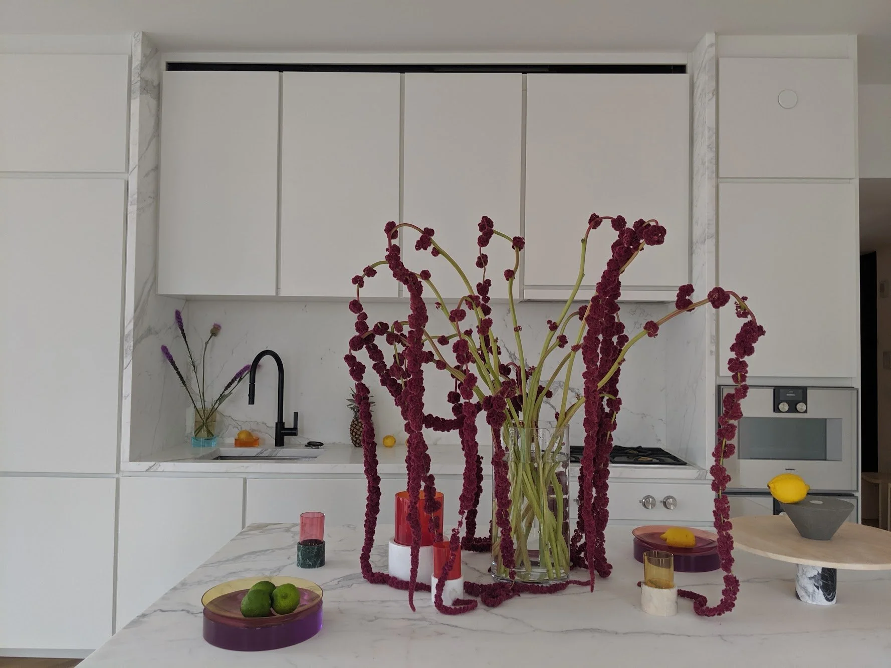  Tall , robust stems with deep red flowers flowing over glass vase 