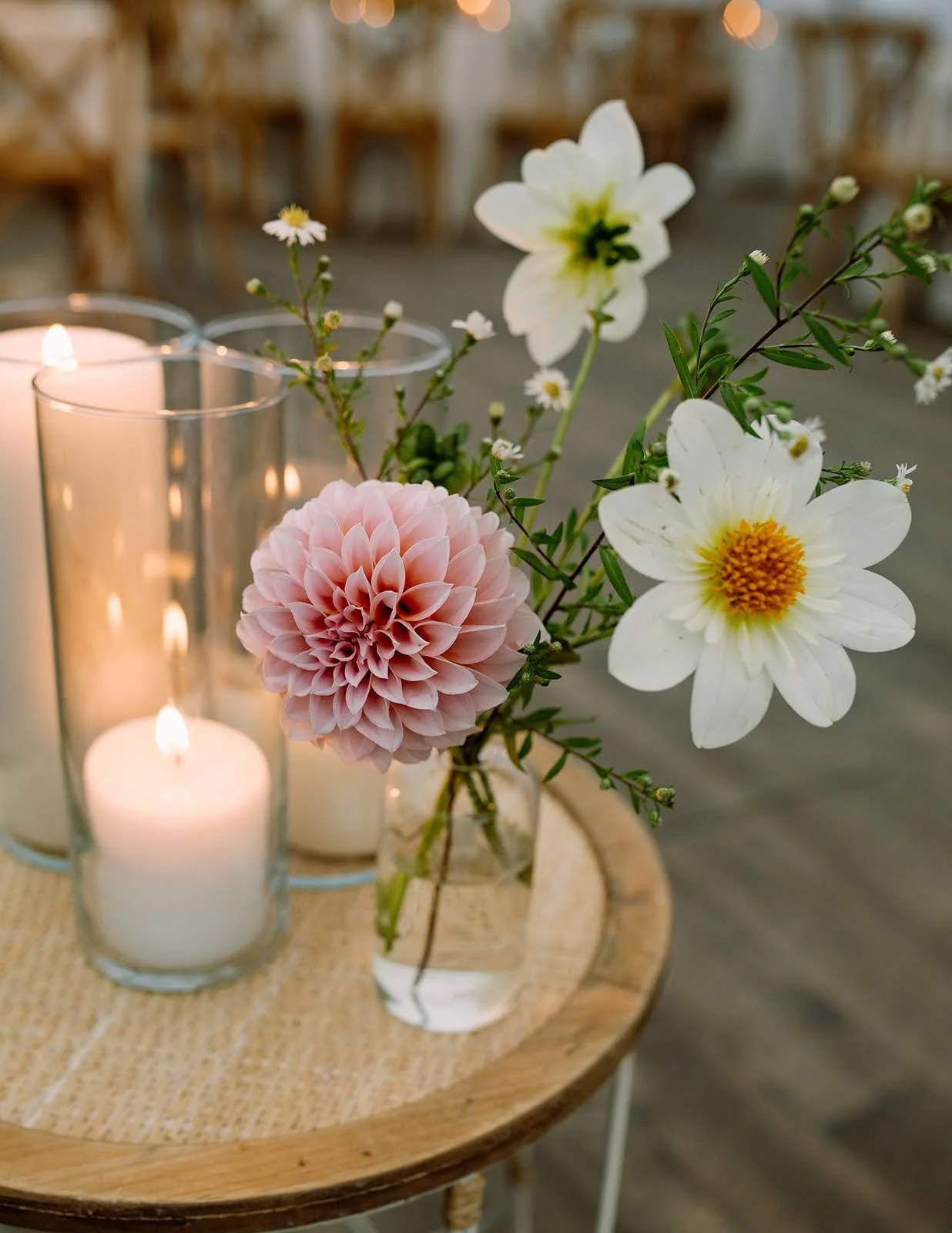  Petite charming bud vase with small delicate pink and white blooms next to pillar candles   
