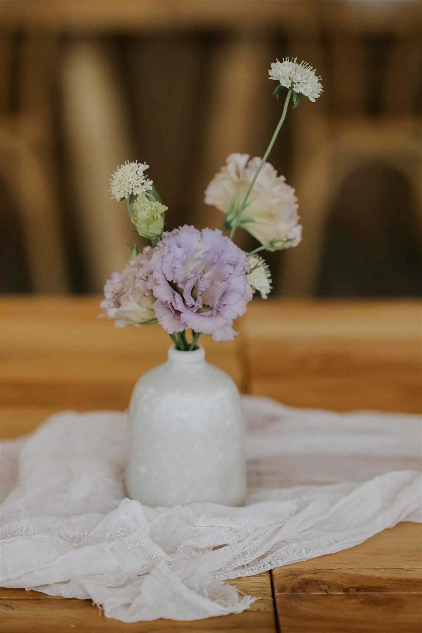  Simple ceramic bud vase on wooden tables featuring ruffled and textured eustomas 