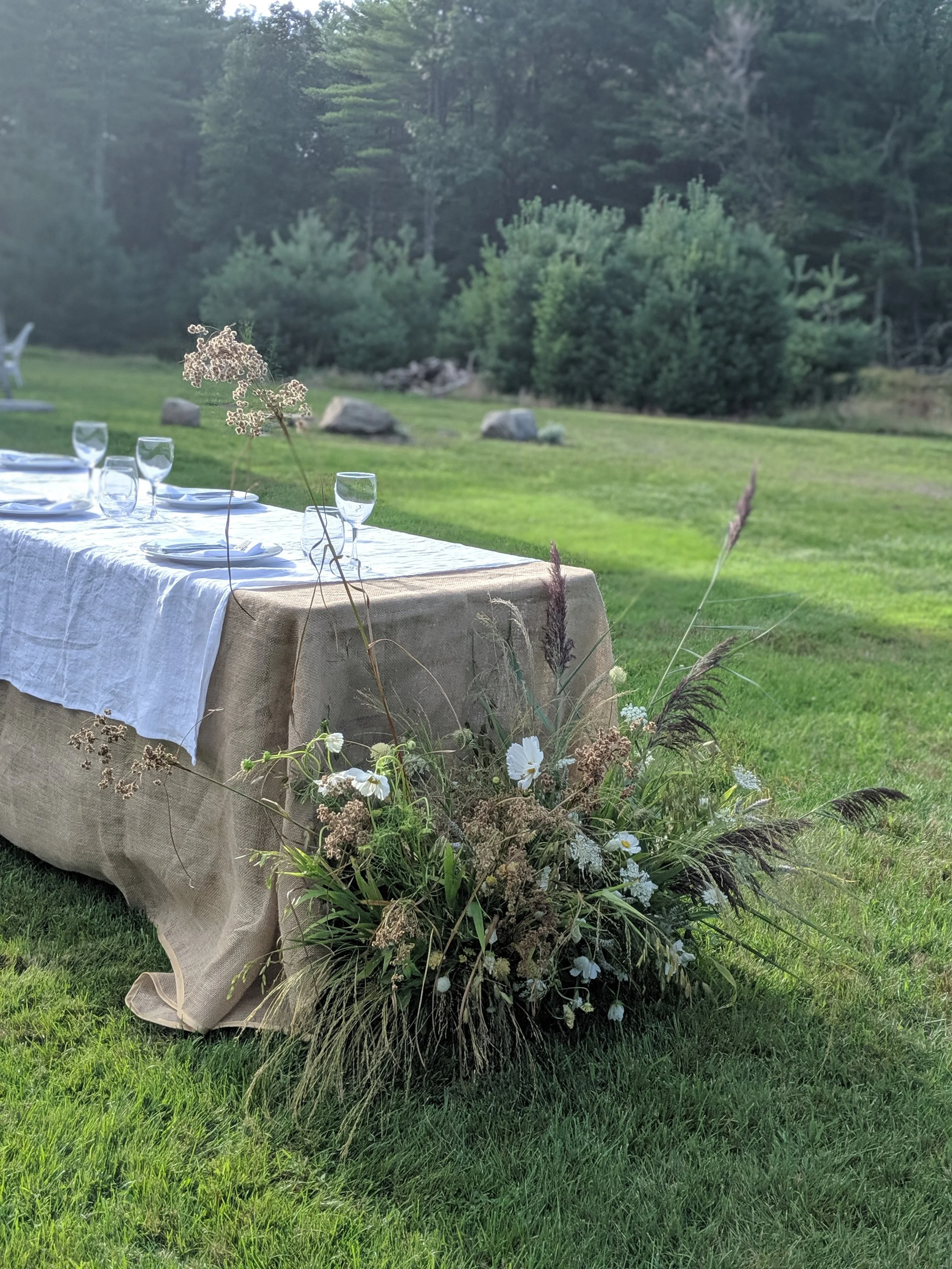  Meadow-inspired arrangement includes fresh and dried grasses at the edge of reception table 