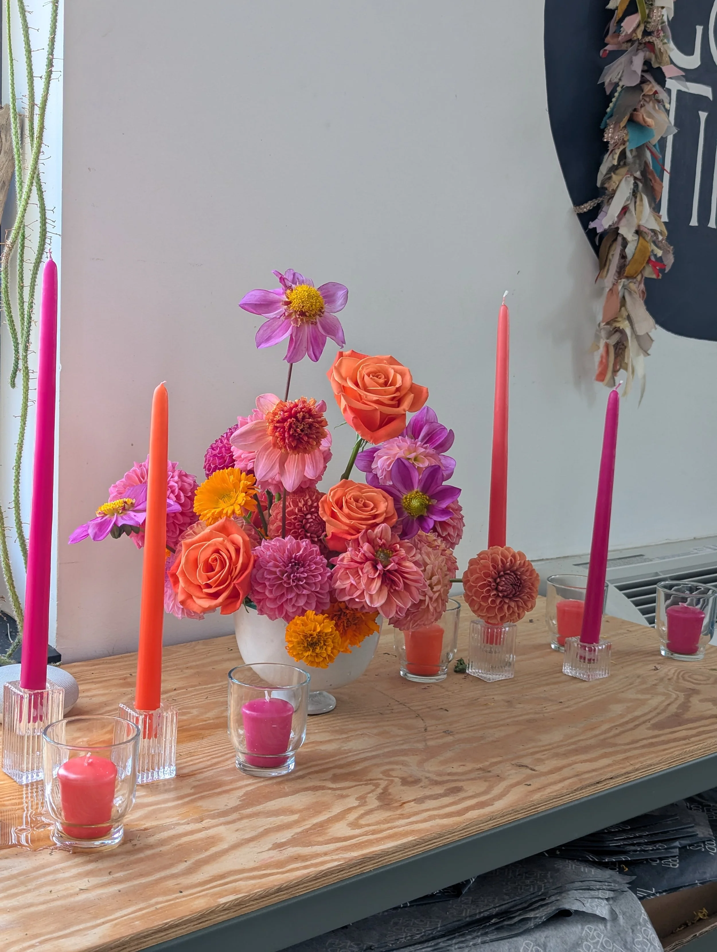  Table curated with dazzling pink and orange candlesticks, votives and matching floral composition in simple ceramic bowl 