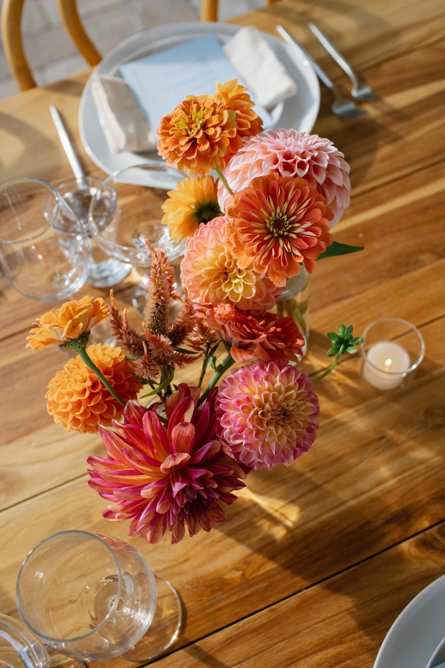  Wooden wedding reception table with showstopping arrangement featuring dahlias of many varieties and colors 