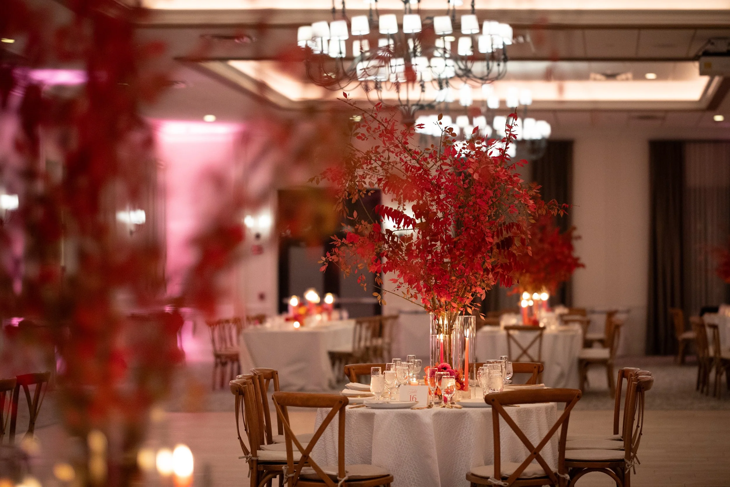  large rustic arrangement sitting in glass on wedding reception table composed entirely of lush red foliage    
