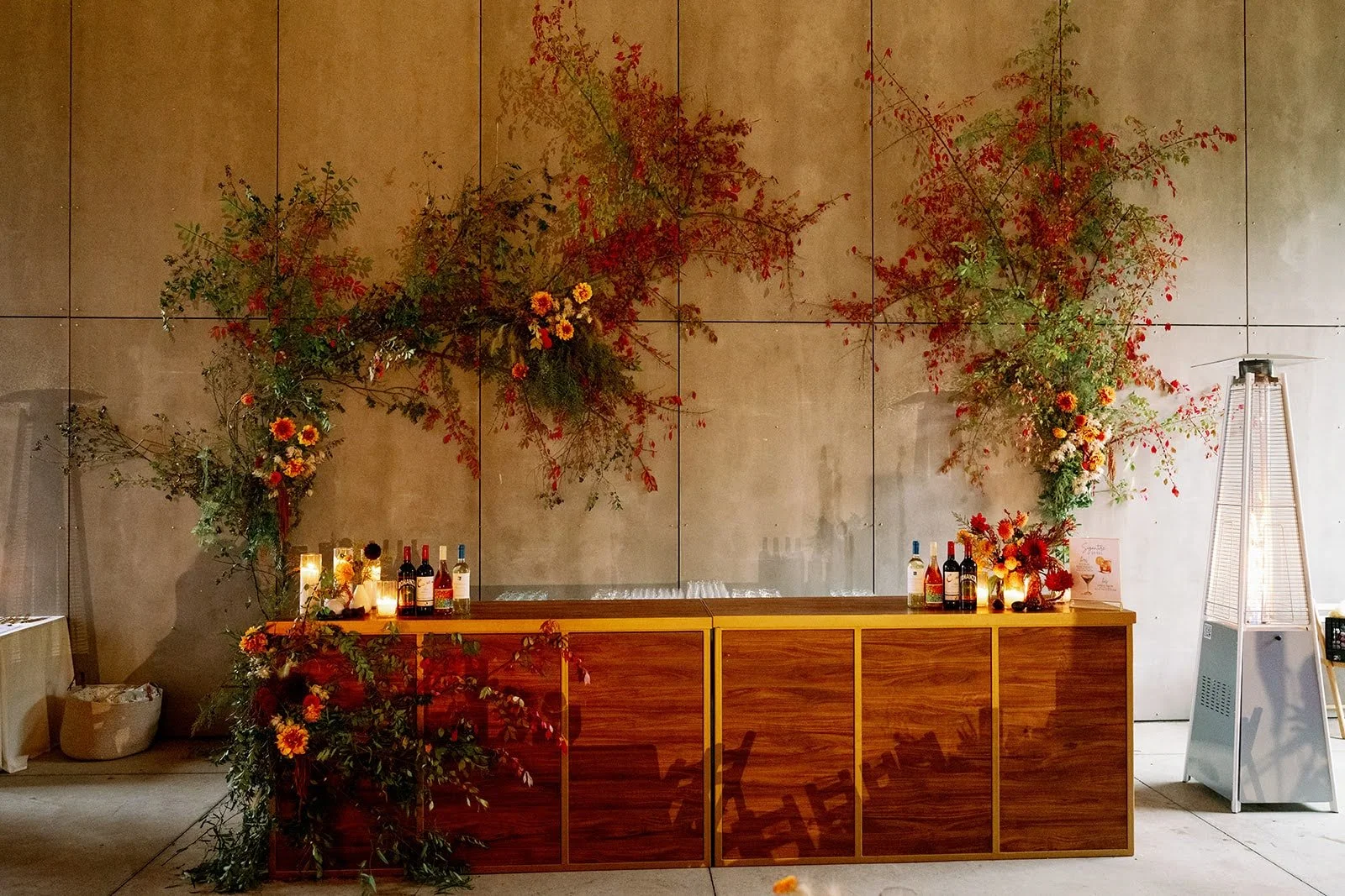  Sculptural floral designs climbing along stone wall have vivid red and green greenery scattered throughout   