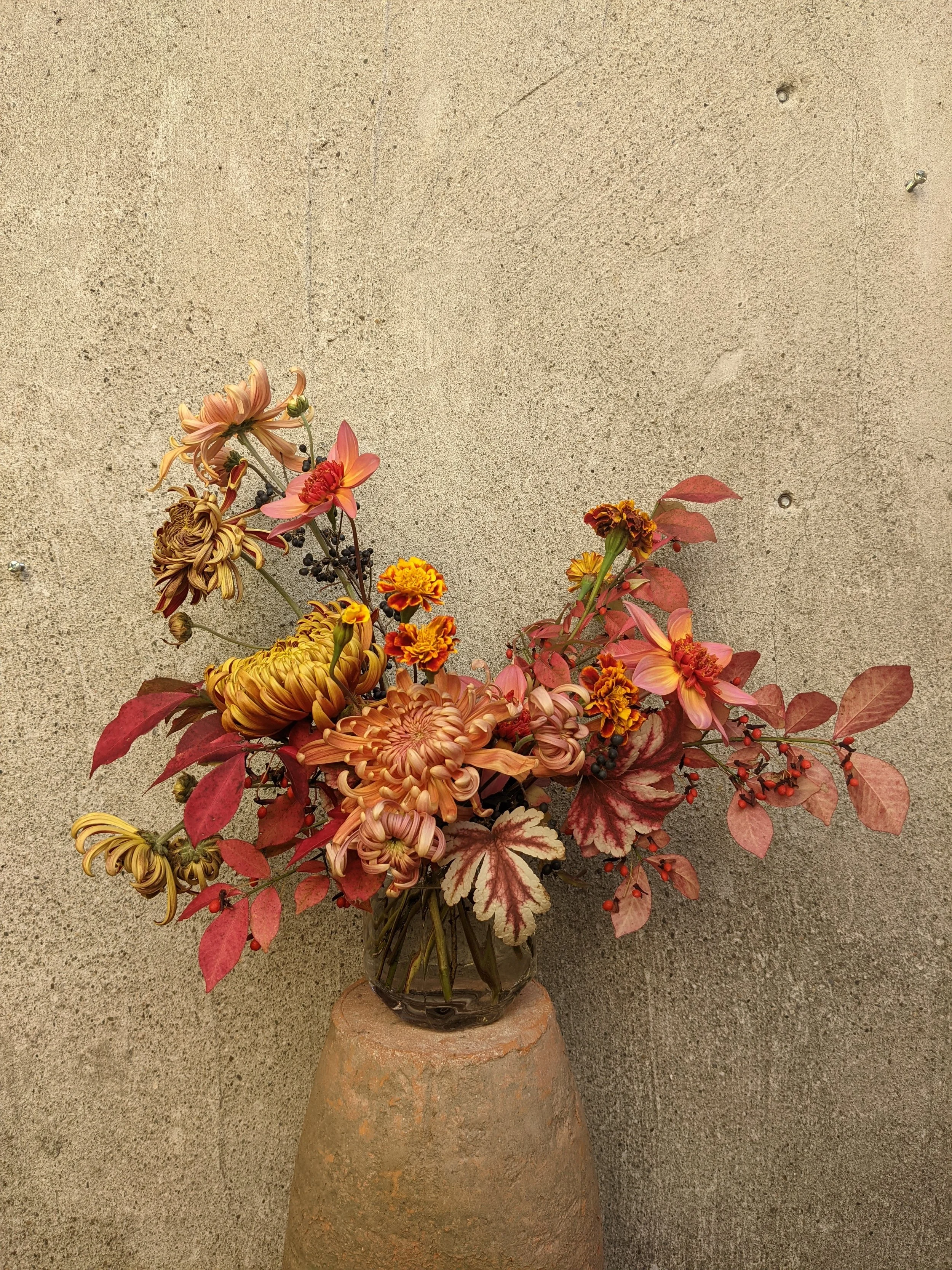  intimate and robust bouquet in simple glass vase featuring various textured flowers and soft pastel leafage  