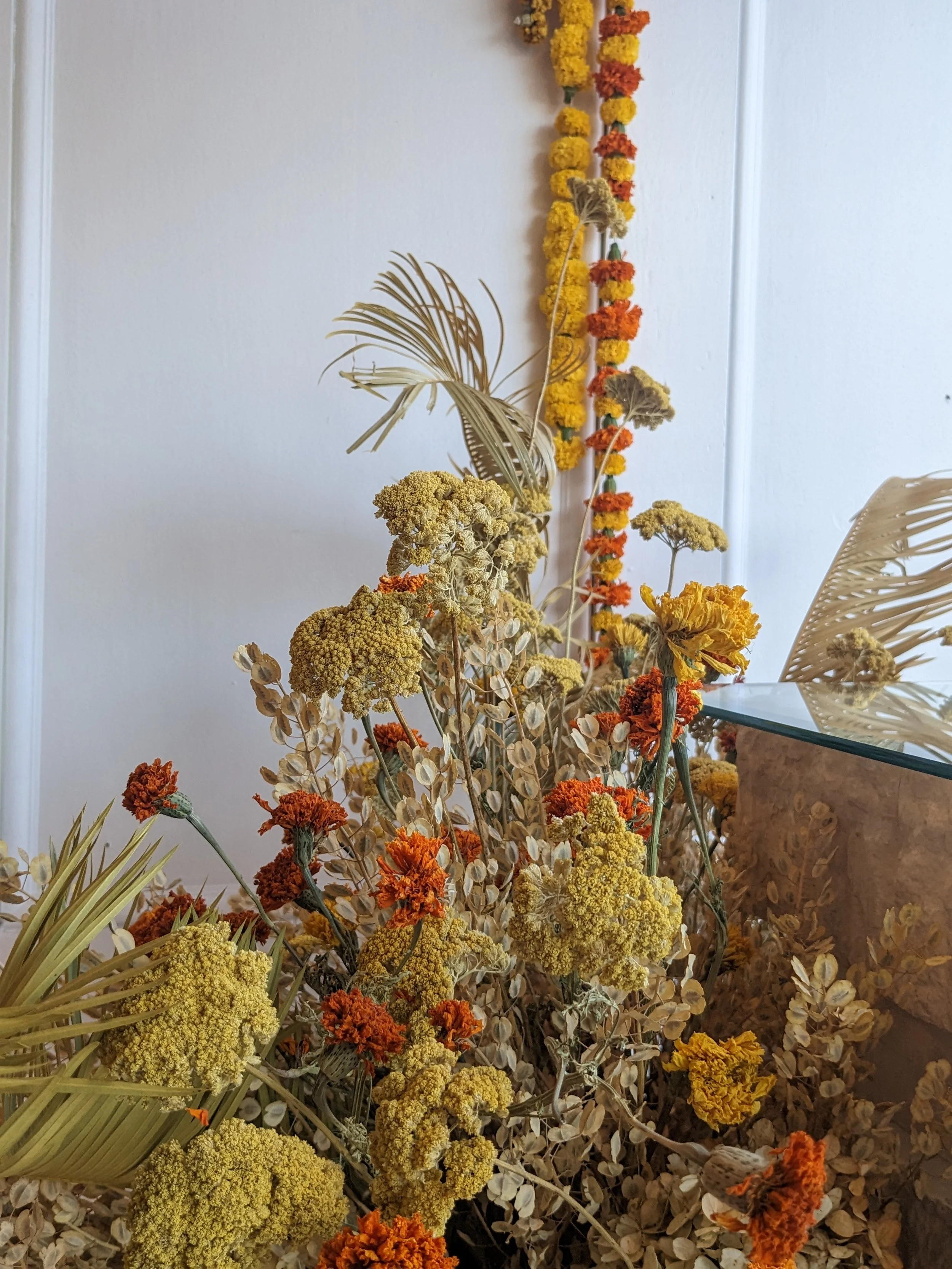  Corner of studio with stuffed with dehydrated arrangements, leaves and vibrant garlands hanging on the wall 