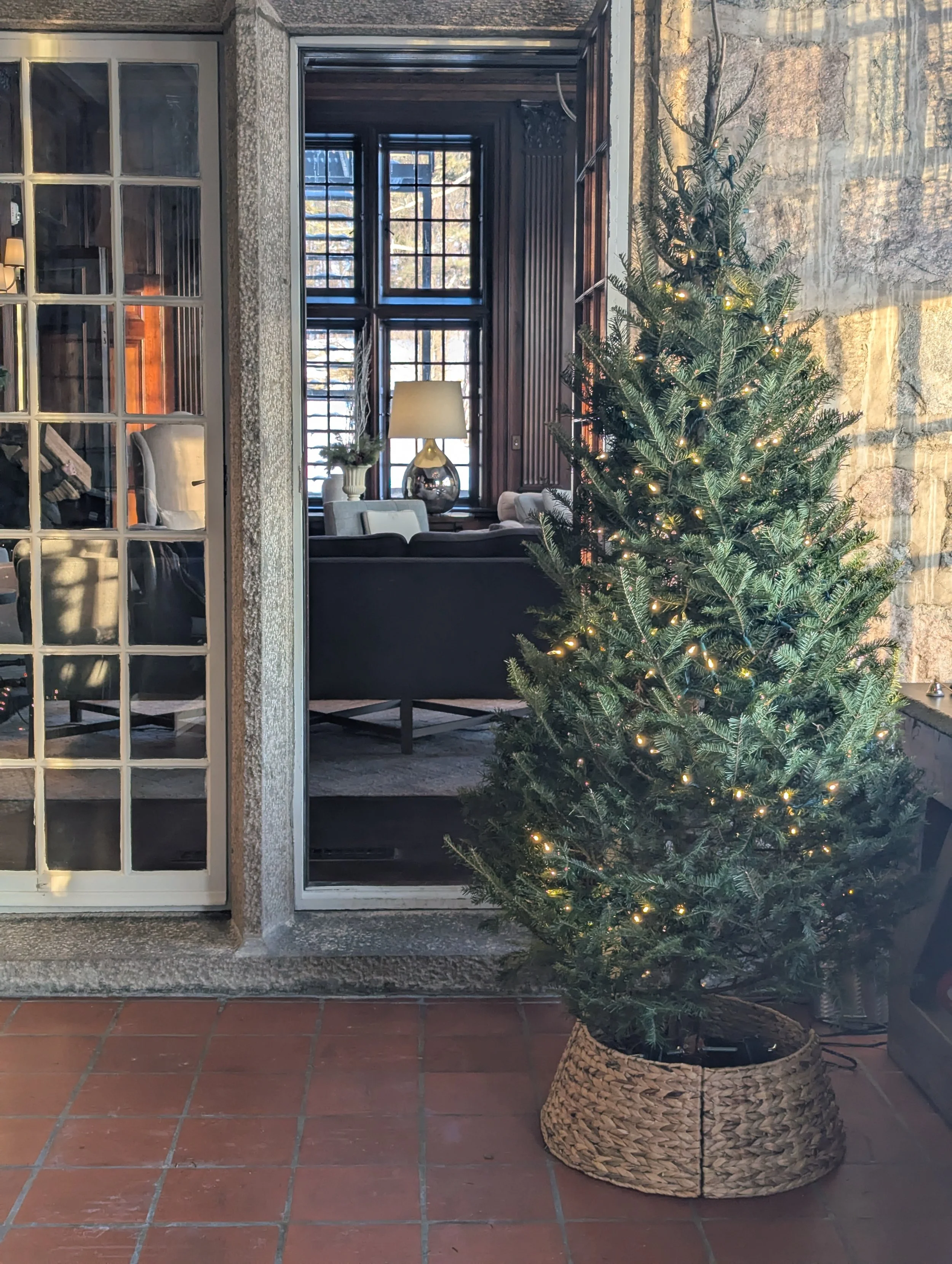  Charming pine tree with simple fairy lights and basic wicker skirt in front of doorway  