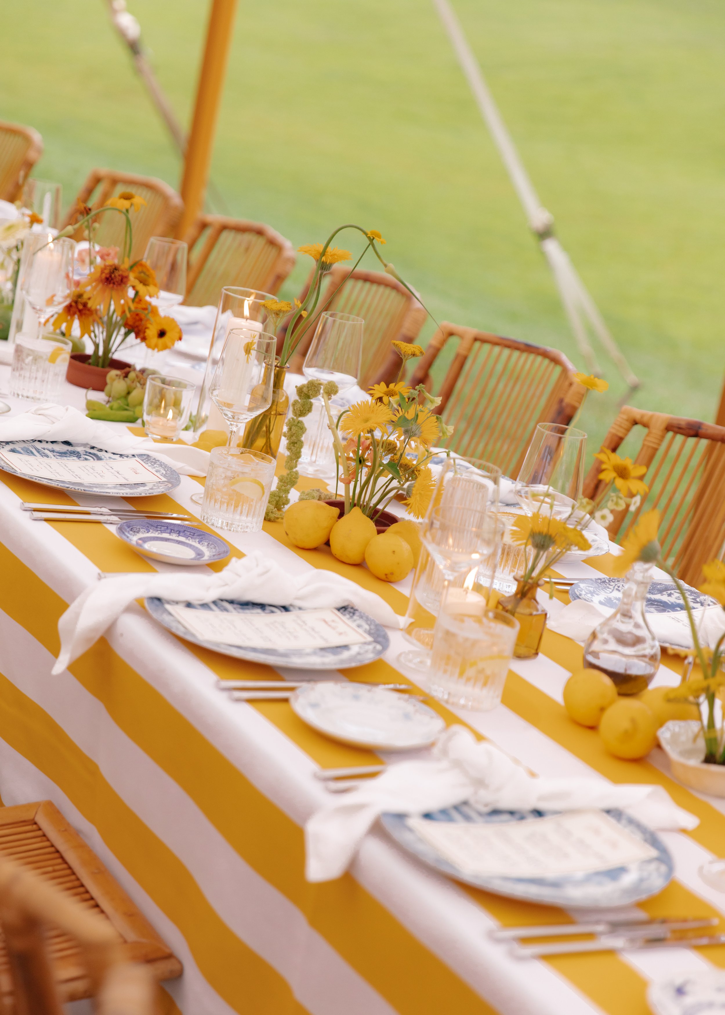 Close-up of yellow-striped reception table with floral centerpieces and citrus accents