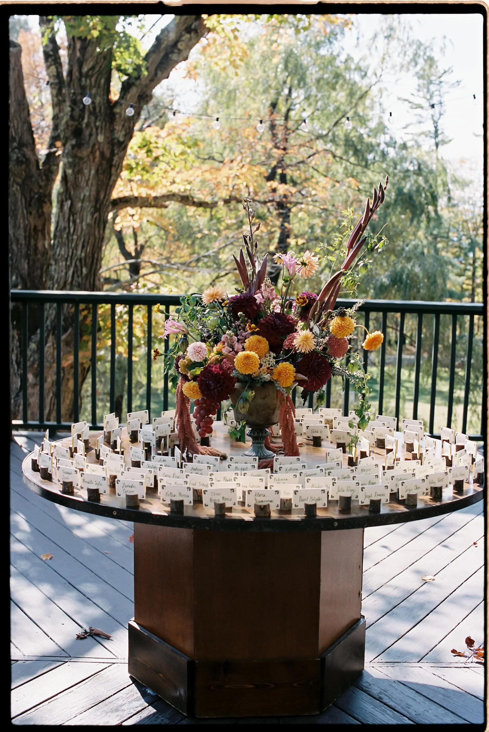 Escort card table styled with a lush fall floral arrangement of dahlias, marigolds, amaranth, and textured foliage