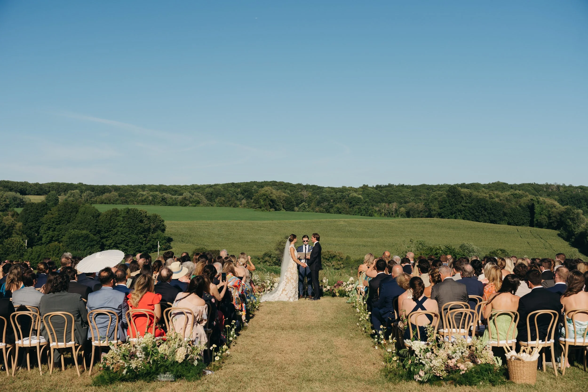 Outdoor wedding ceremony with guests seated in a meadow at private residence