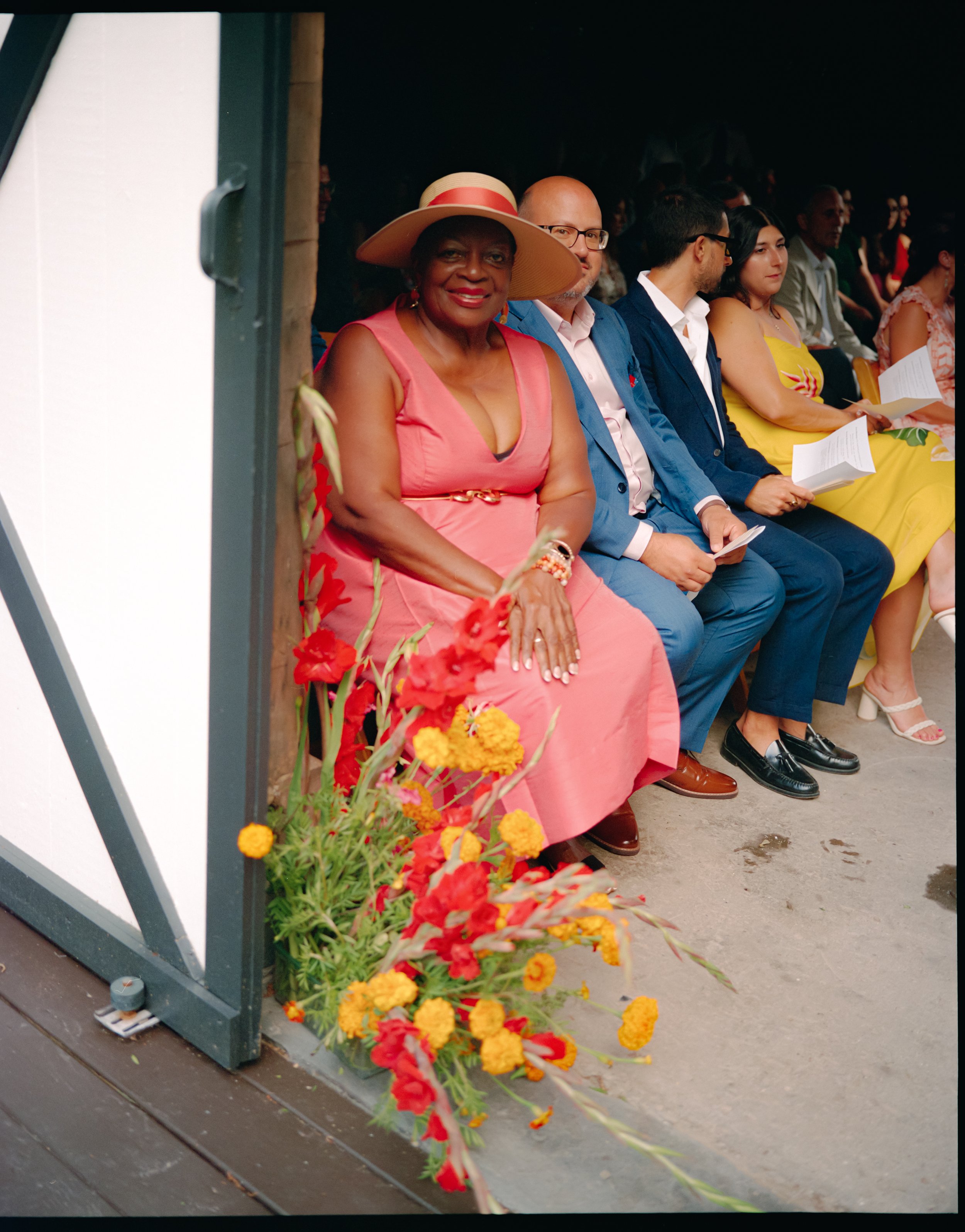 Guests seated inside barn ceremony space with colorful floral installations