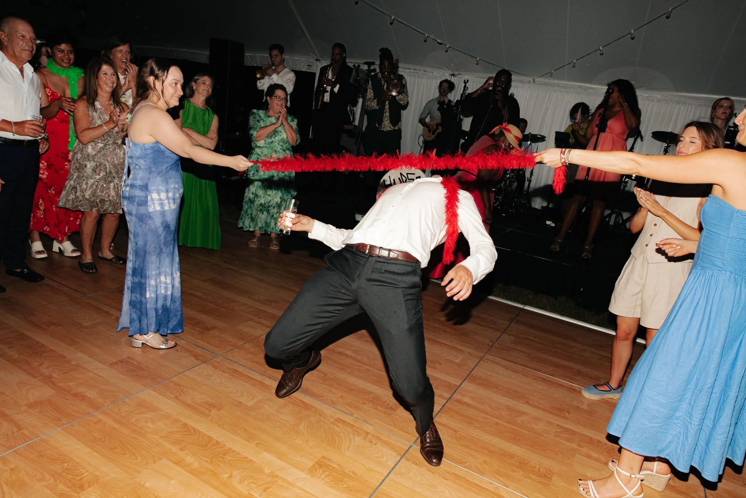 Wedding guests dancing and playing limbo during lively estate reception