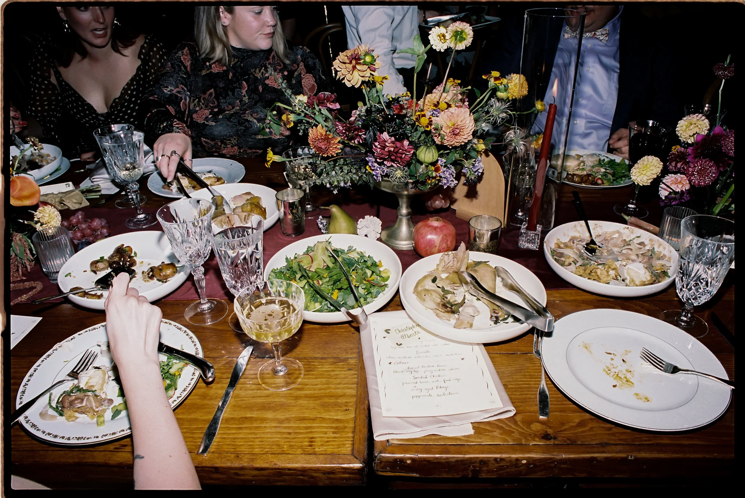 Intimate dinner table layered with lush fall floral centerpiece, seasonal fruit, and taper candles among place settings