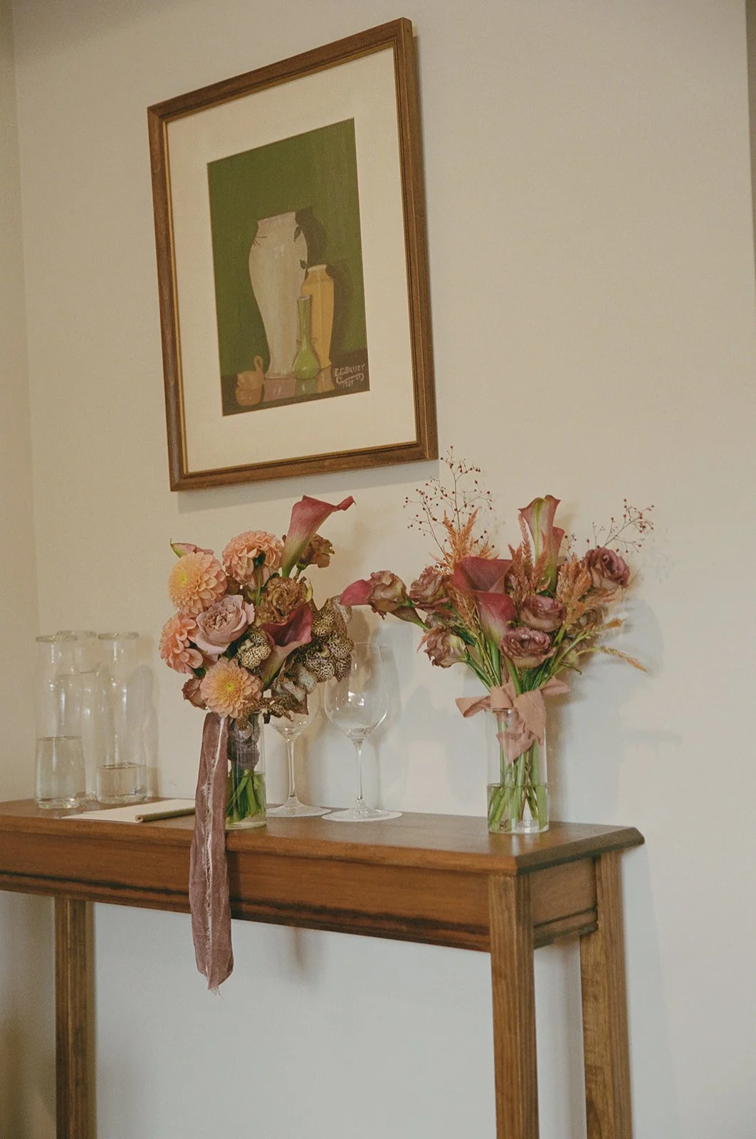 Seasonal floral bouquets in soft blush and peach tones arranged on a wooden console table indoors.