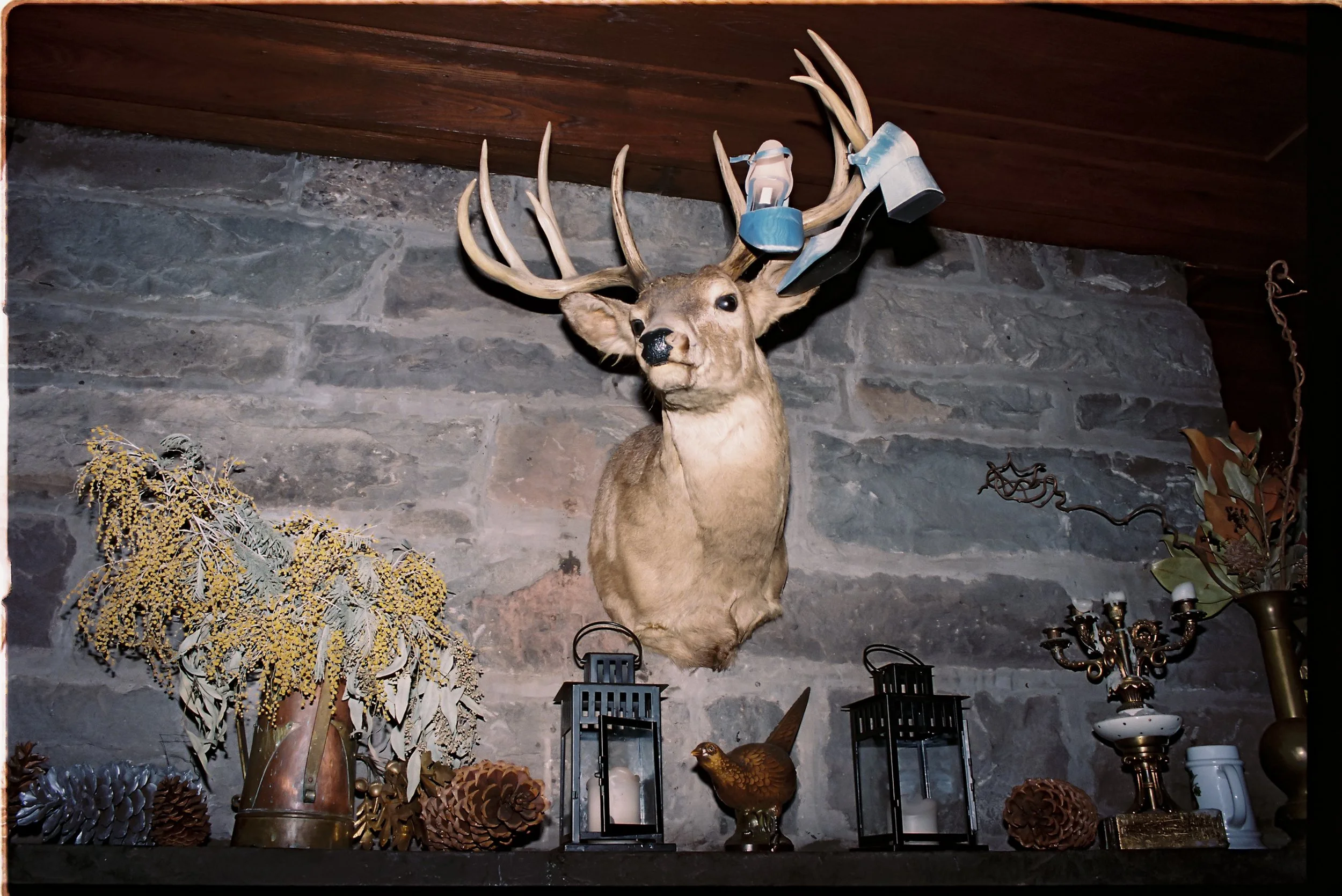 Mantel vignette styled with dried florals, foraged textures, and autumnal elements beneath a rustic lodge setting
