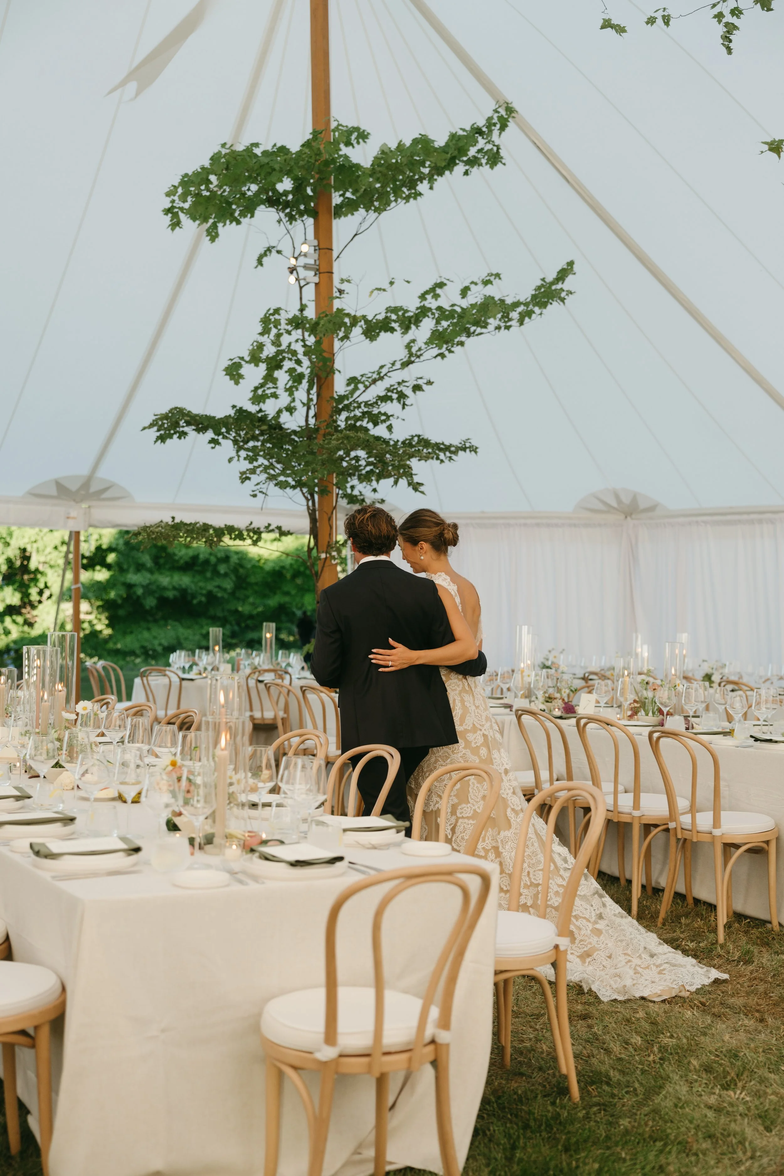Garden-style table florals surrounding bride and groom inside sailcloth tent