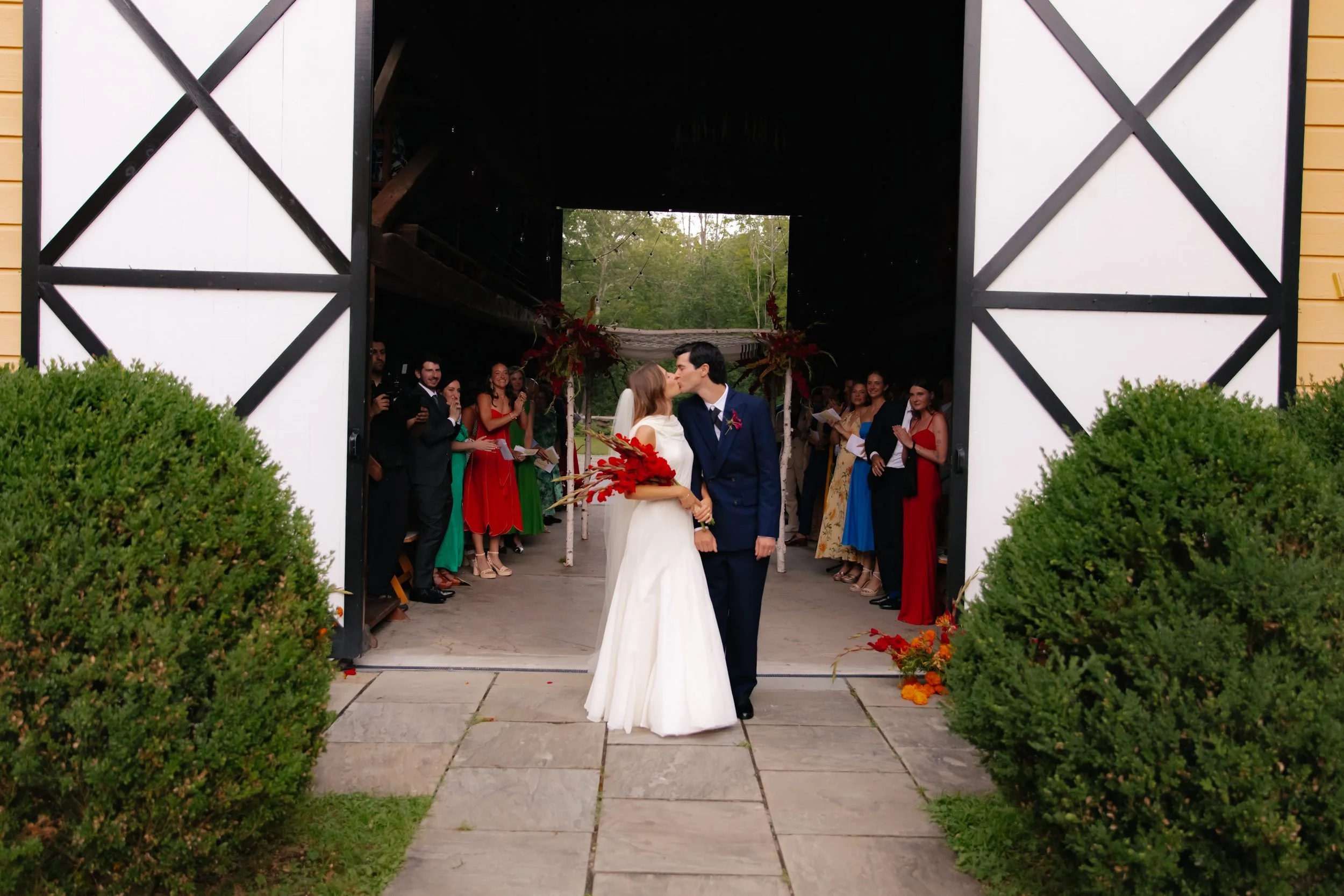Bride and groom sharing a kiss at barn entrance after ceremony