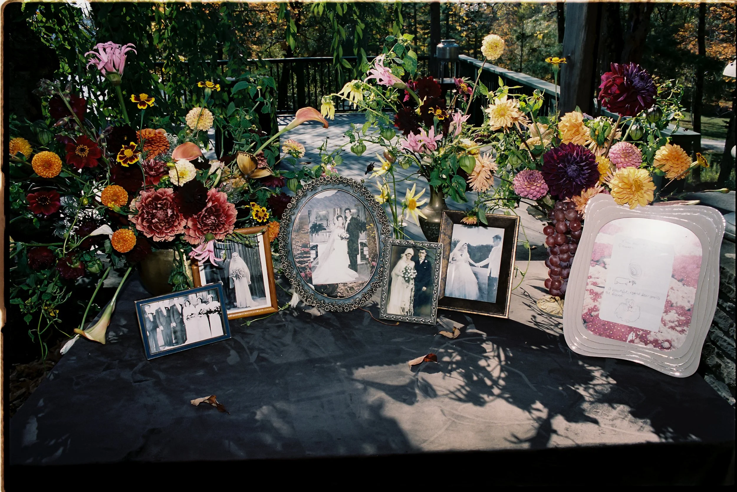 Memorial table styled with framed photographs and abundant fall florals in rich, moody tones