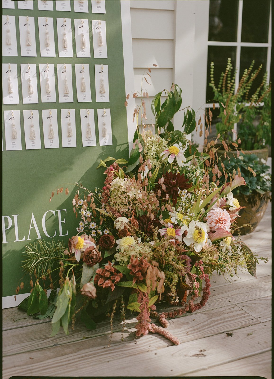 Loose, garden-inspired floral installation surrounding escort cards with layered blooms and trailing foliage.