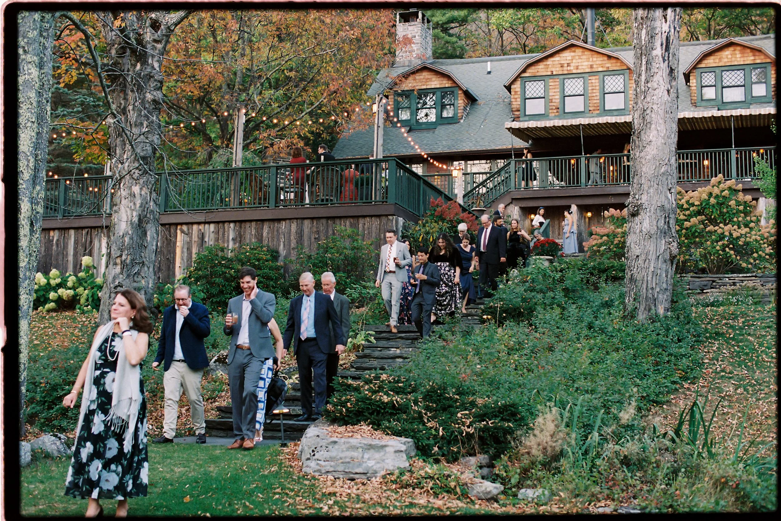 Guests walking through the Deer Mountain Inn grounds framed by early autumn foliage and natural greenery