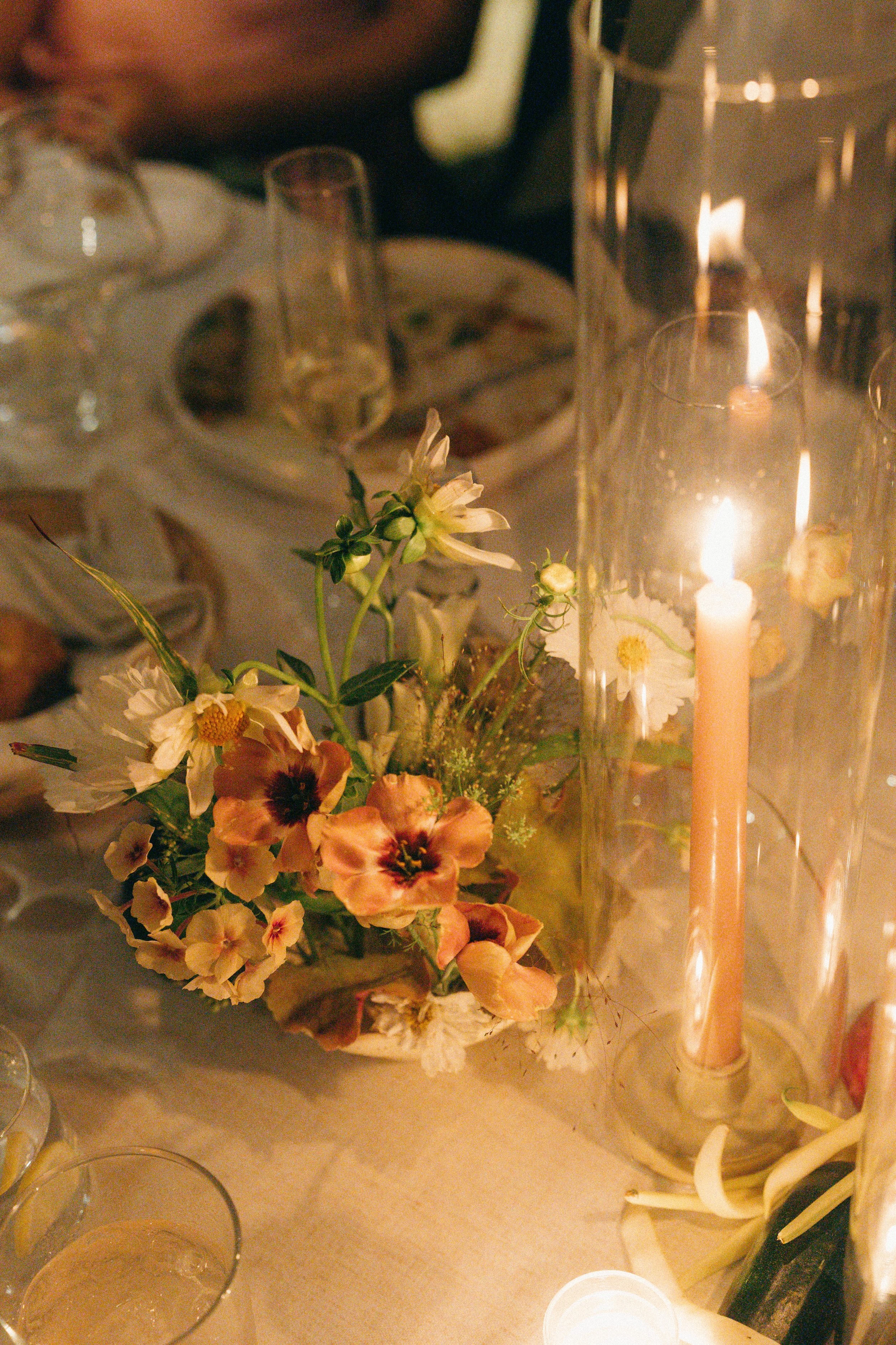 Petite floral arrangement with blush blooms and taper candle in glass holder