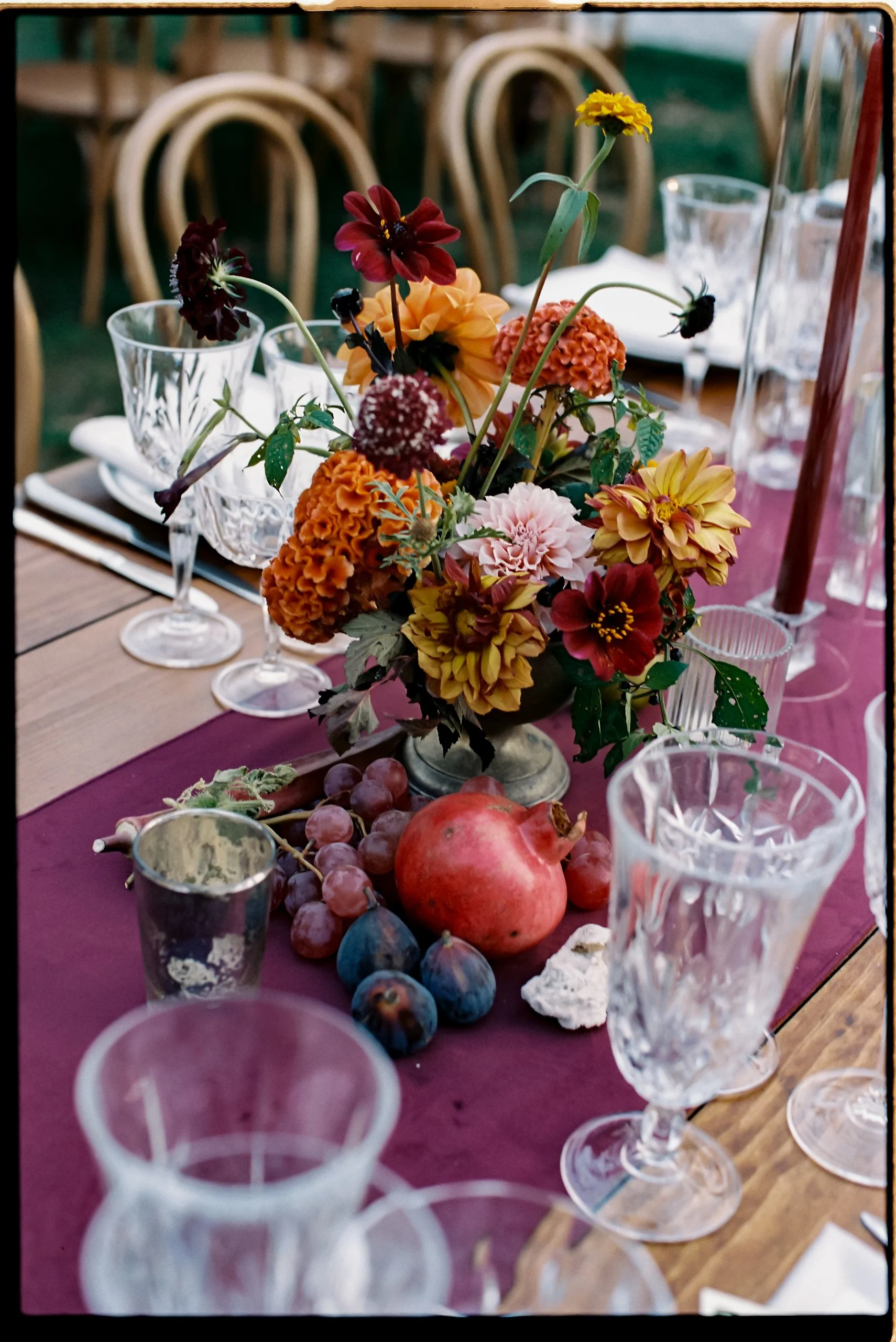 Low floral centerpiece layered with seasonal fruit accents and garden-inspired textures